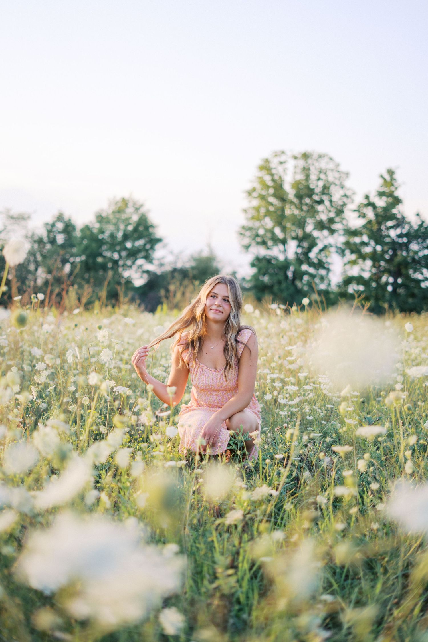A dreamy summer portrait in a wildflower meadow with soft lighting and a pink floral dress.