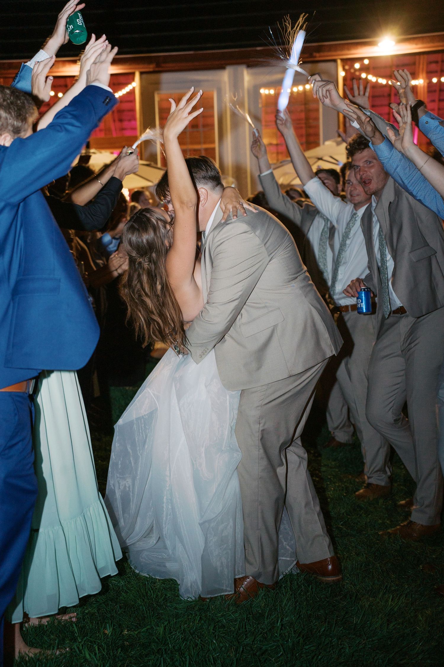 Wedding guests dancing with hands raised during nighttime reception.
