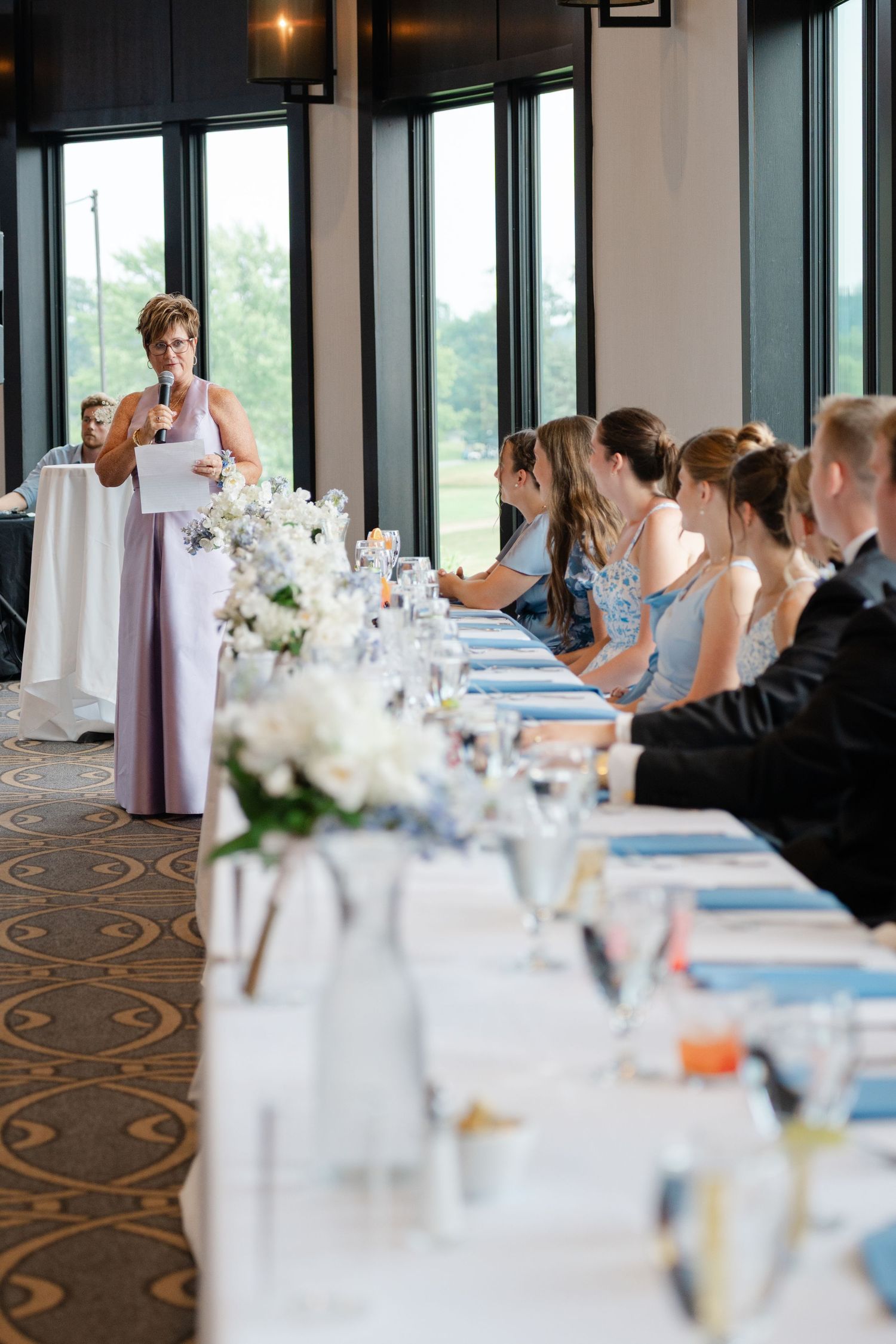 Reception speech being delivered at elegant wedding dinner with formal table settings.