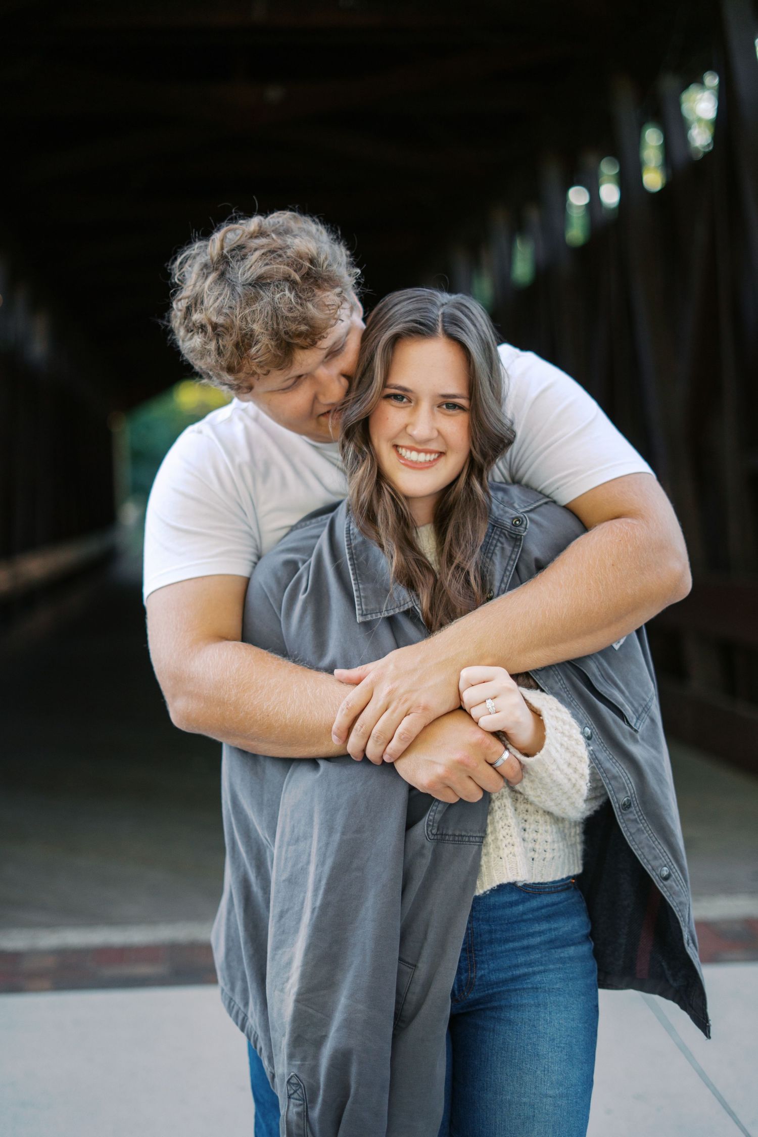 Couple laughing and hugging while wearing casual outfits.