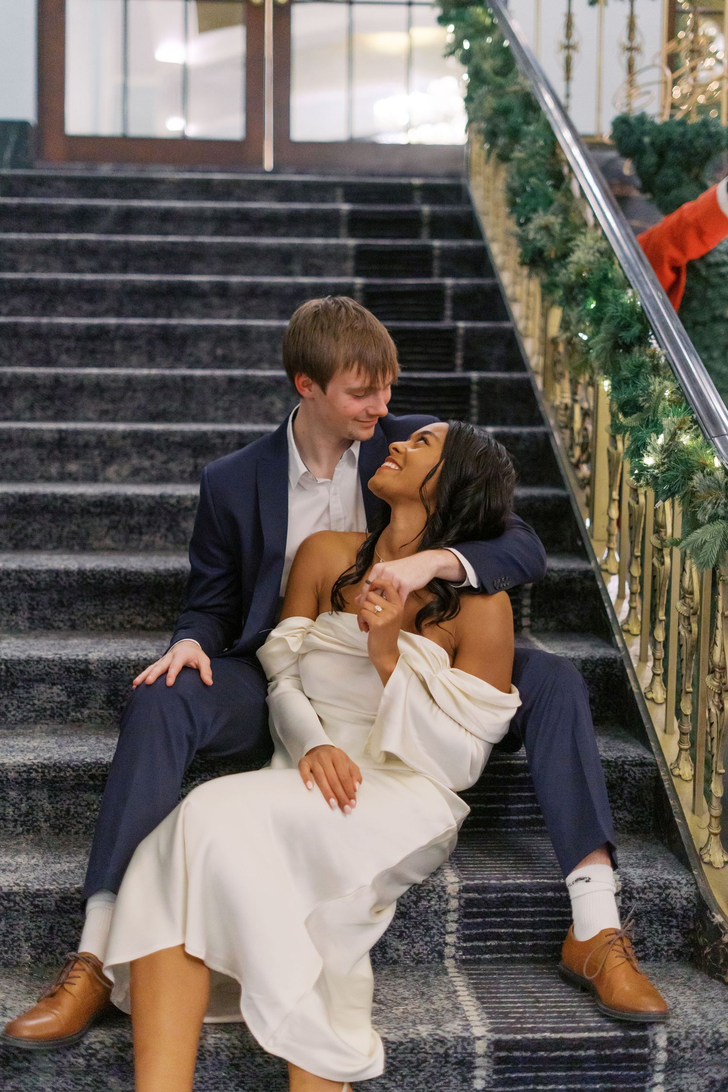 A romantic couple shares playful moments on elegant stone steps.