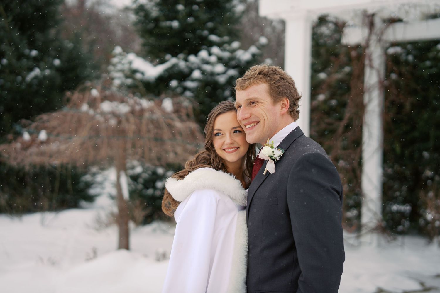Couple shares romantic winter wedding moment outdoors in the snow.