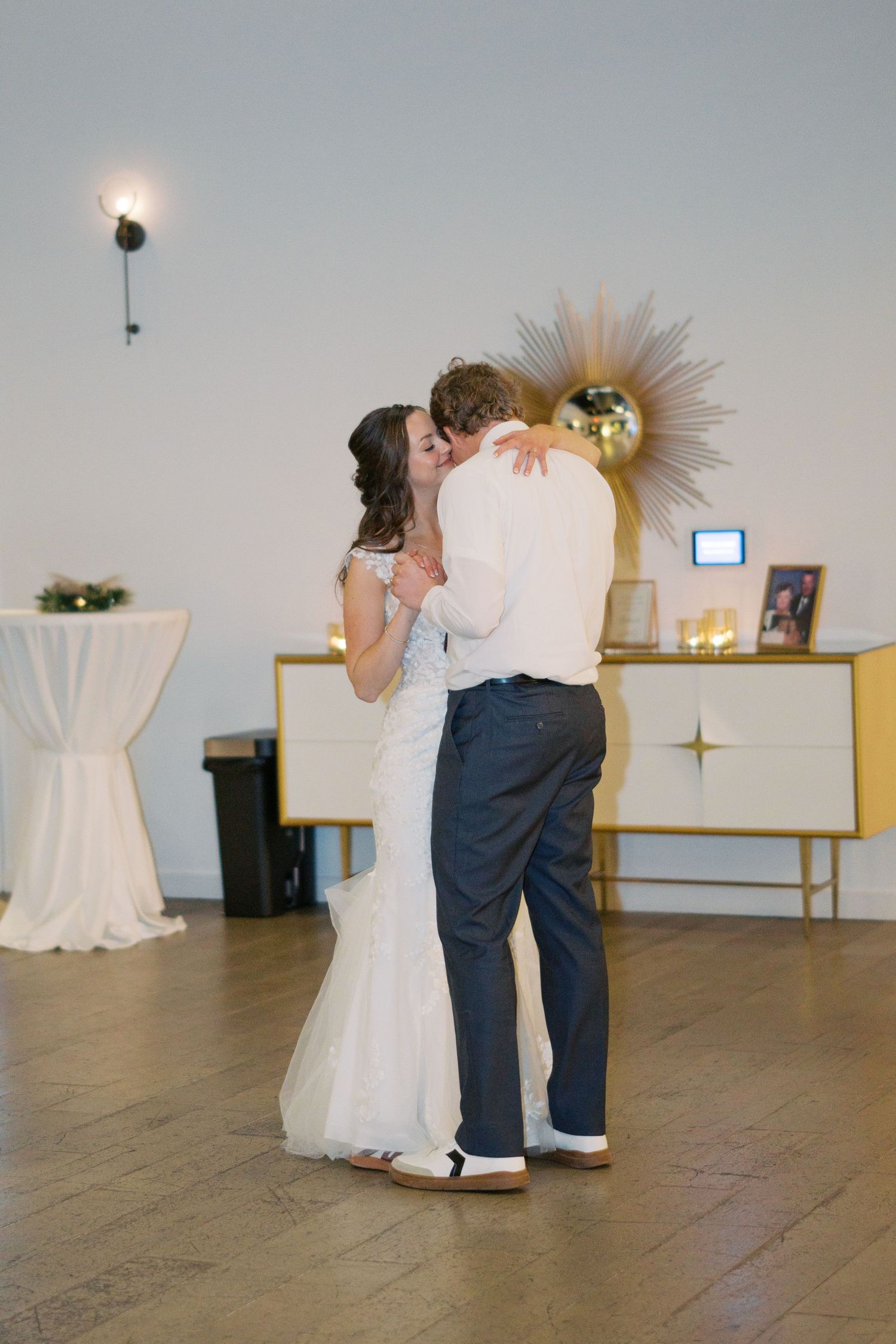 Couples dancing in an elegant white-walled venue with wooden floors.
