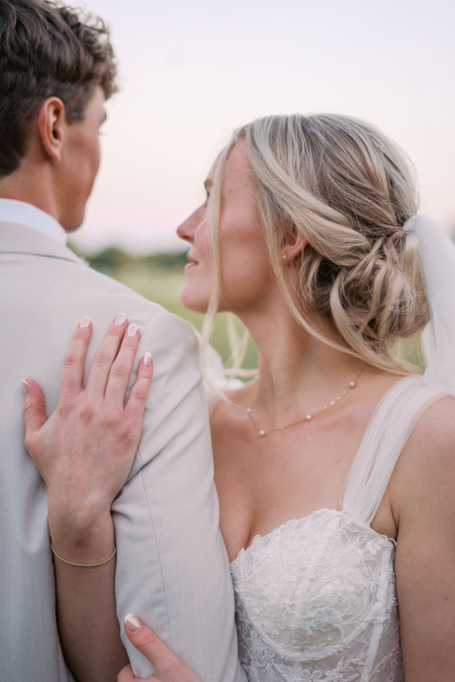 Romantic portrait of newlyweds embracing in soft evening light.