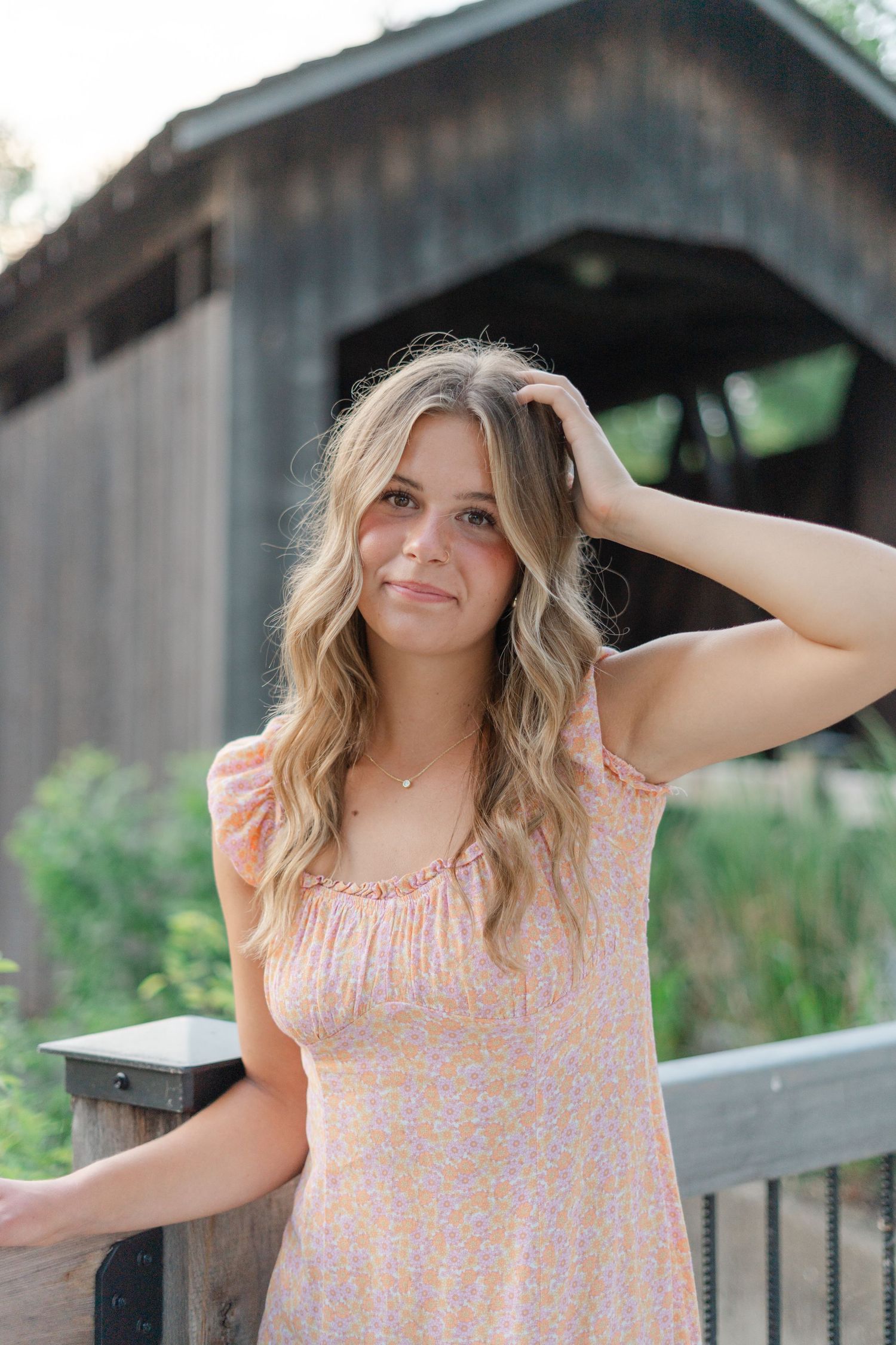 A series of outdoor portraits showing someone in a peach floral summer dress against a rustic barn backdrop.
