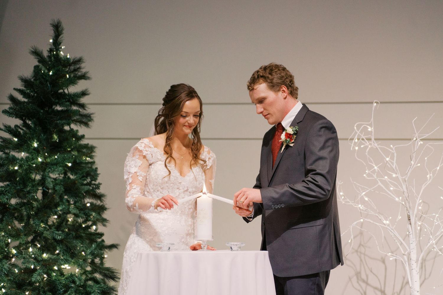 Indoor wedding ceremony moments with Christmas trees and white decorations in the background.