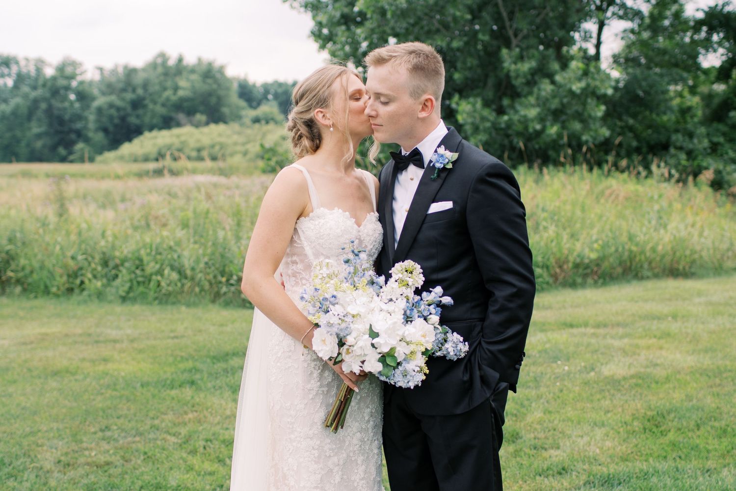 Wedding party poses in formal attire against a natural outdoor backdrop.