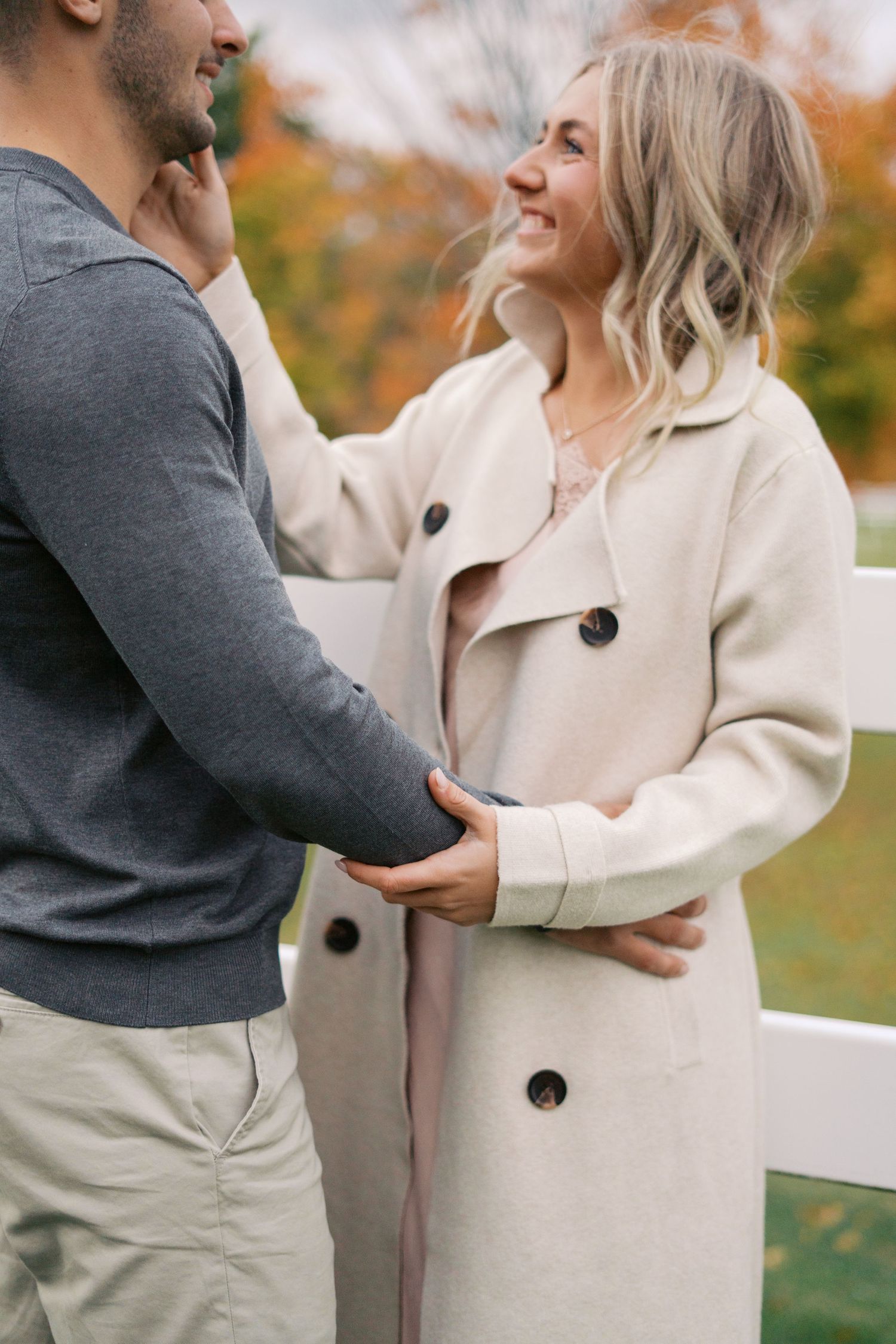 A romantic moment between two people wearing coordinated cream and gray outfits outdoors.