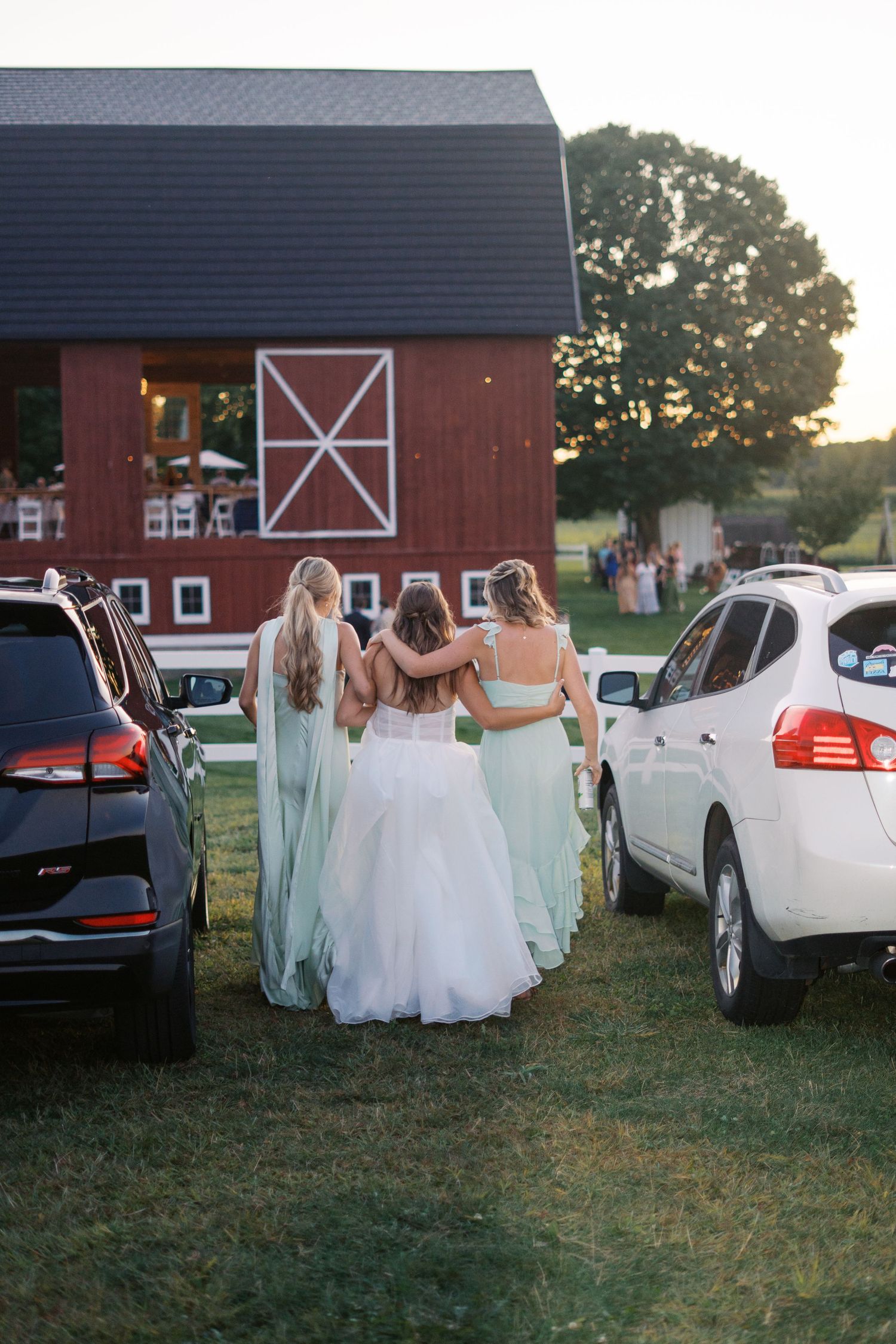 Group in formal attire walking together near a red barn building.