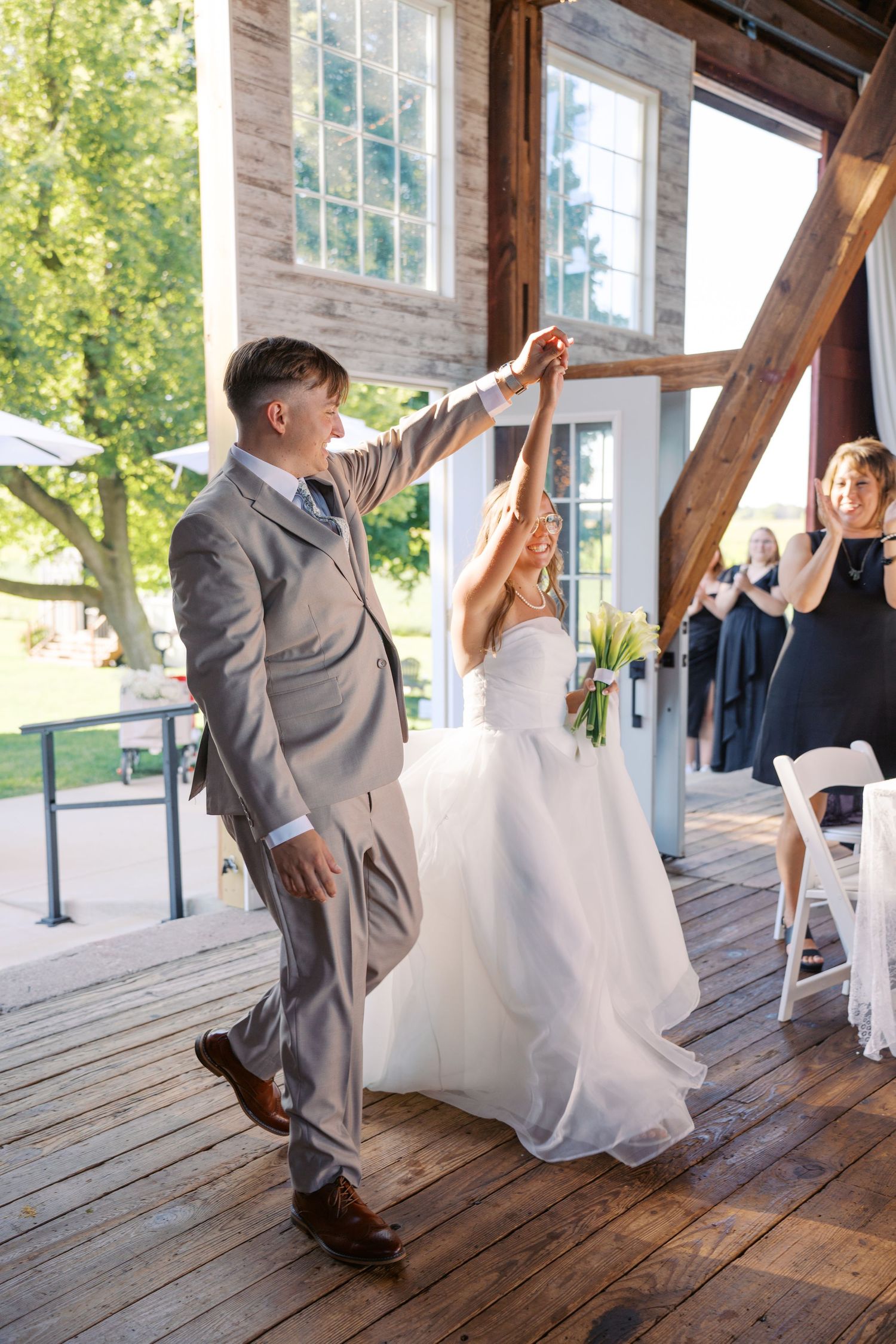 Wedding couple dances playfully on a rustic wooden deck.
