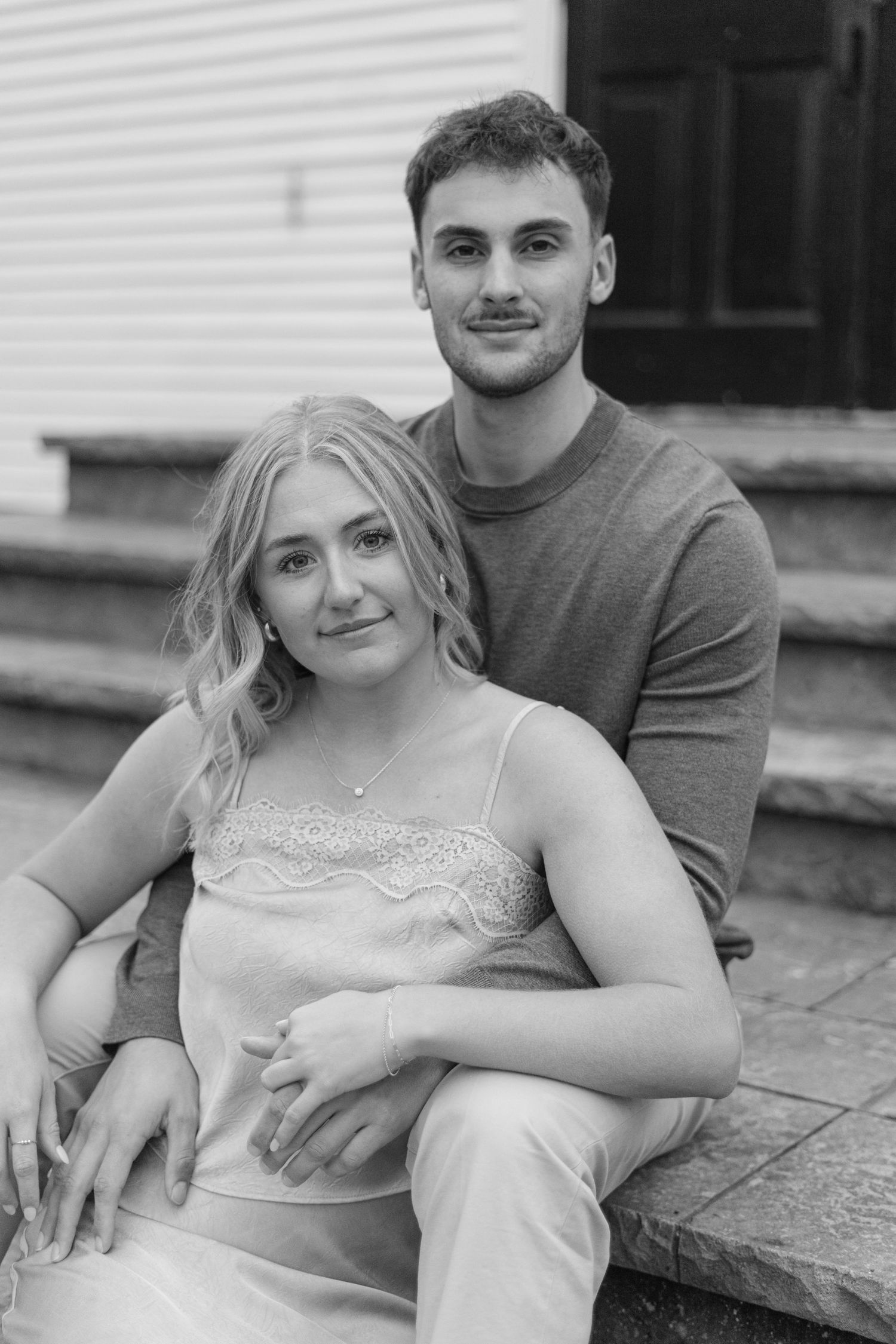 Couple sitting together on stone steps in casual engagement photo session.