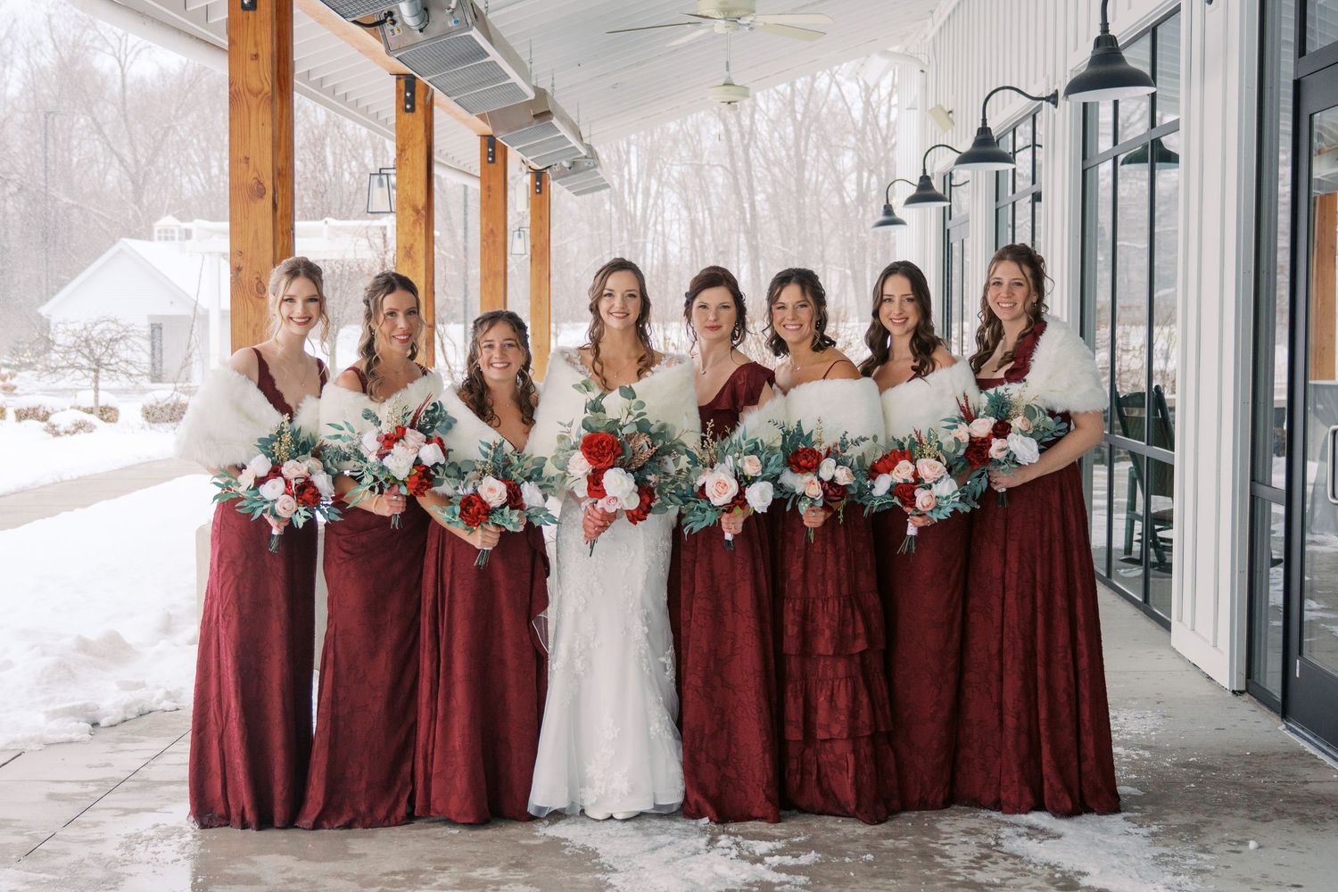 Wedding party in burgundy dresses and navy suits posing in winter setting.