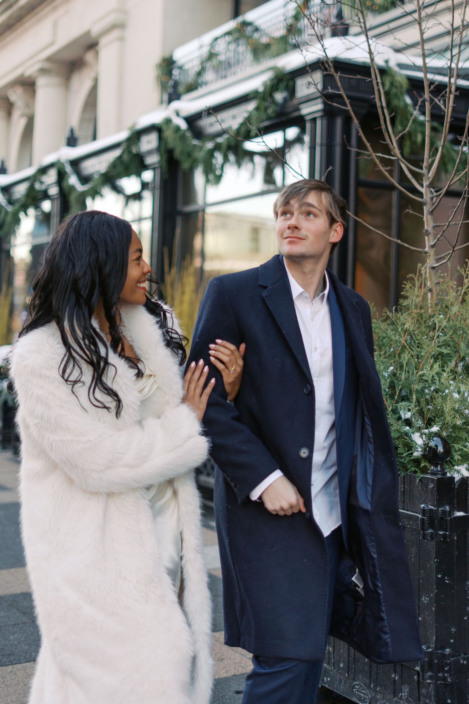 Couple in contrasting outfits of navy and white embrace while standing on a city street.
