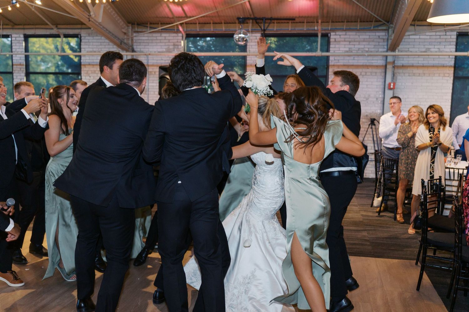 Wedding guests dance in formation during a lively reception celebration.