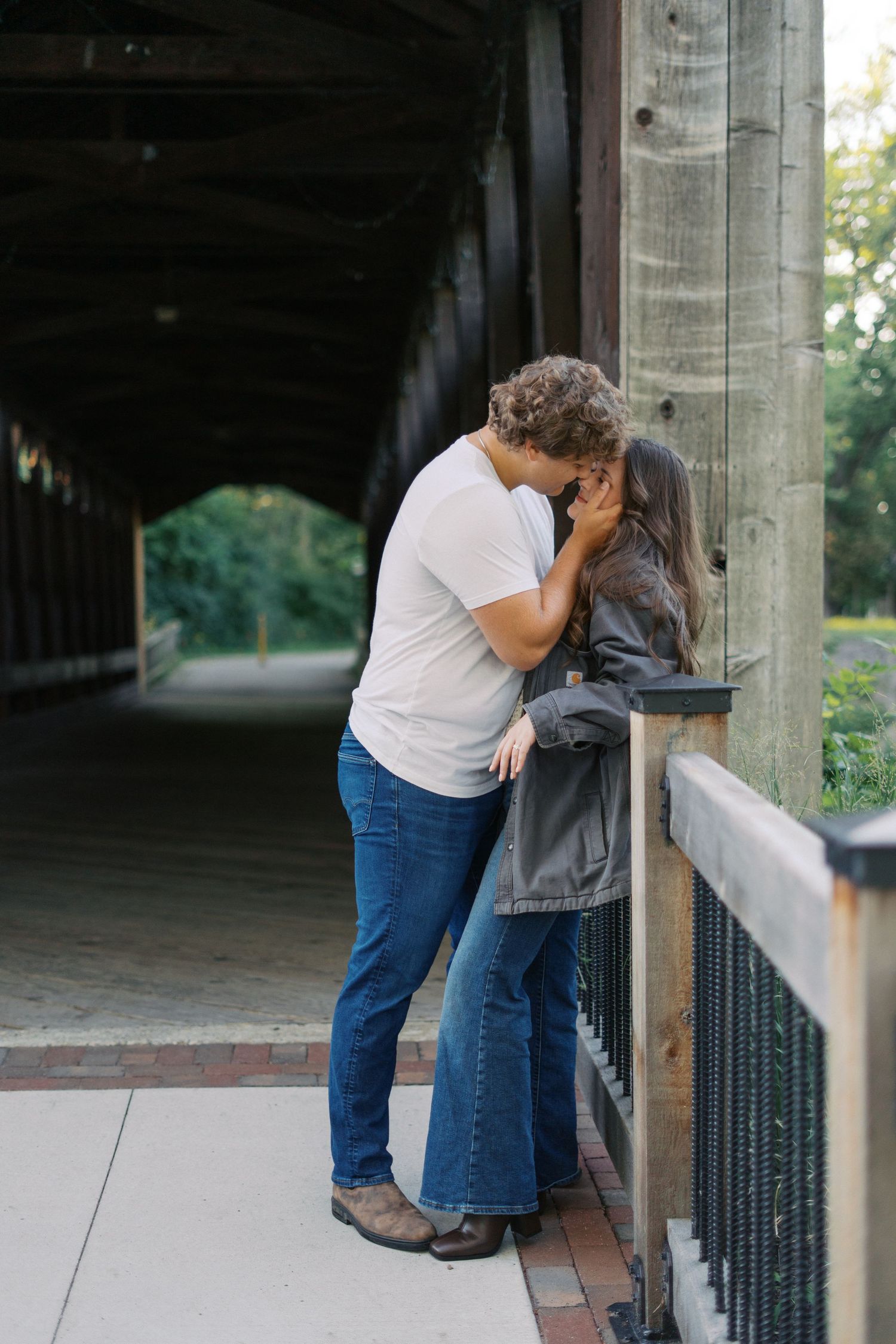 Couple sharing intimate moments along a covered walkway with concrete pillars.