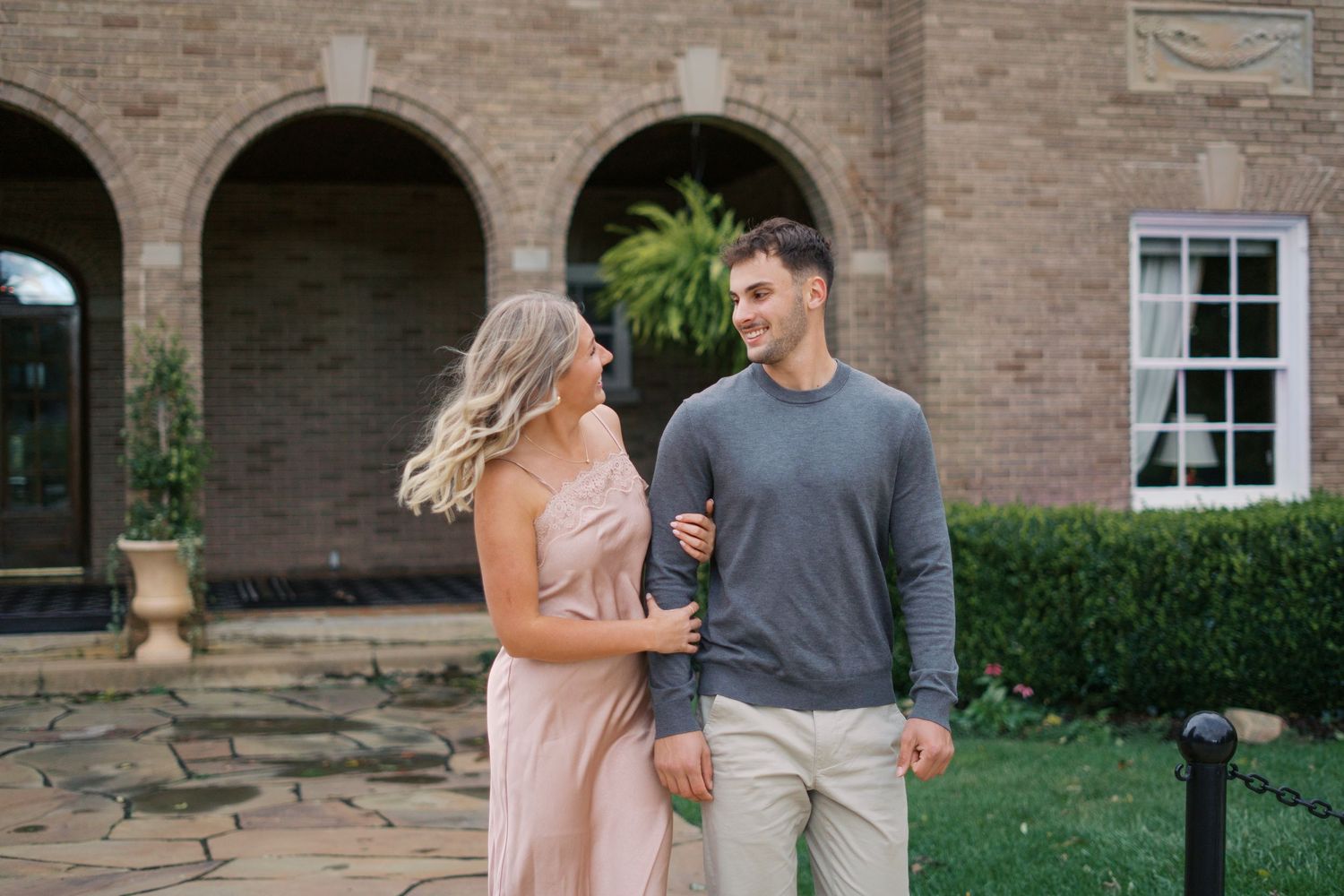 Couple walking together along brick building exterior in casual attire.