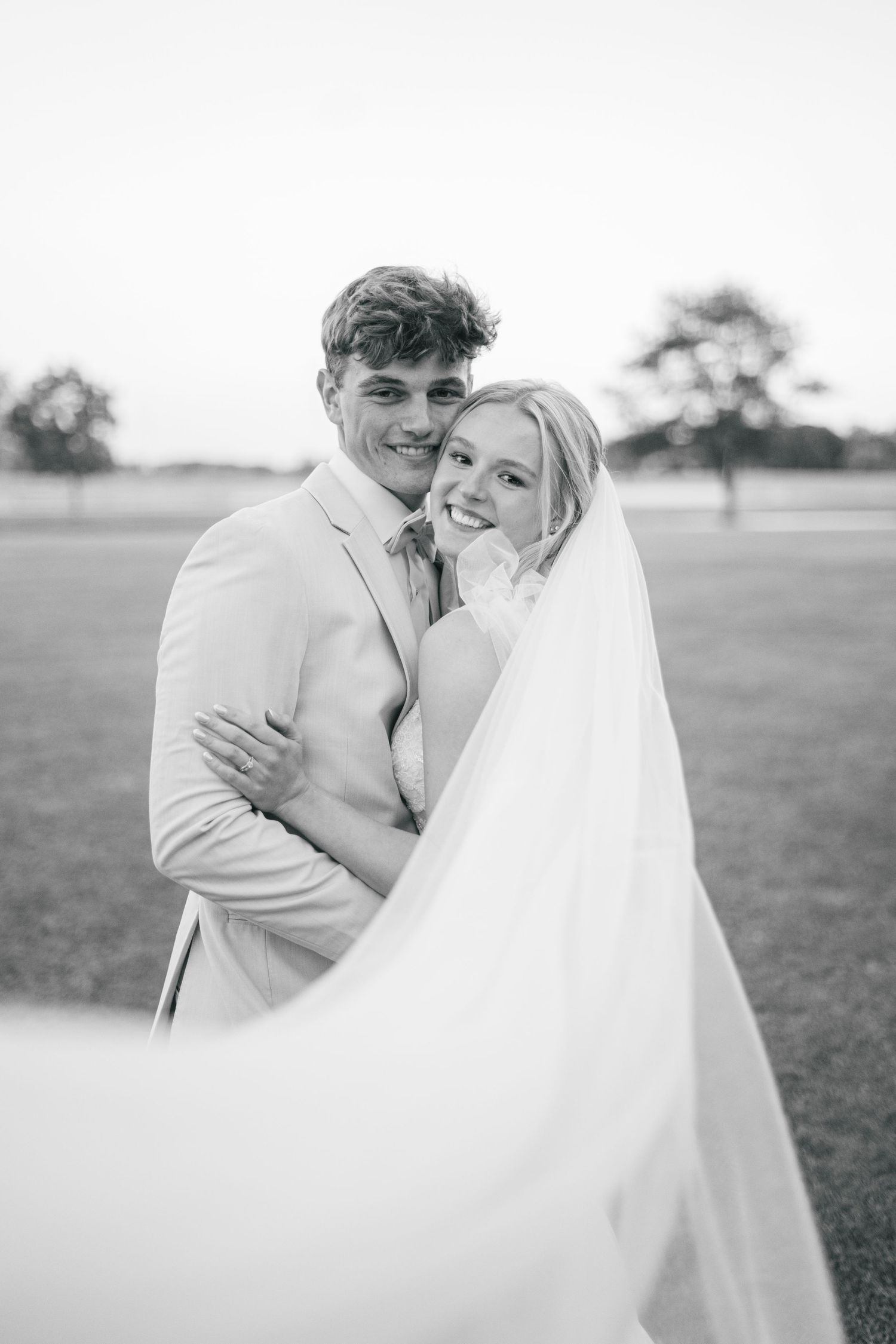 Black and white portraits of newlyweds sharing intimate moments in a field.