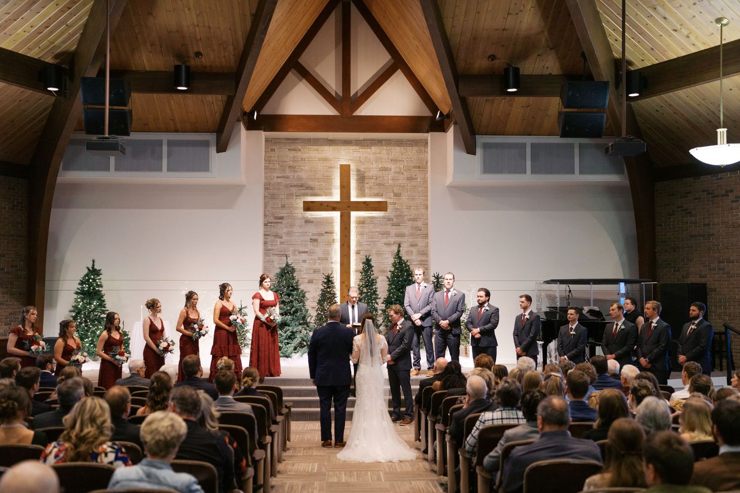 Church wedding ceremony in a modern chapel with exposed wooden beams and cross.
