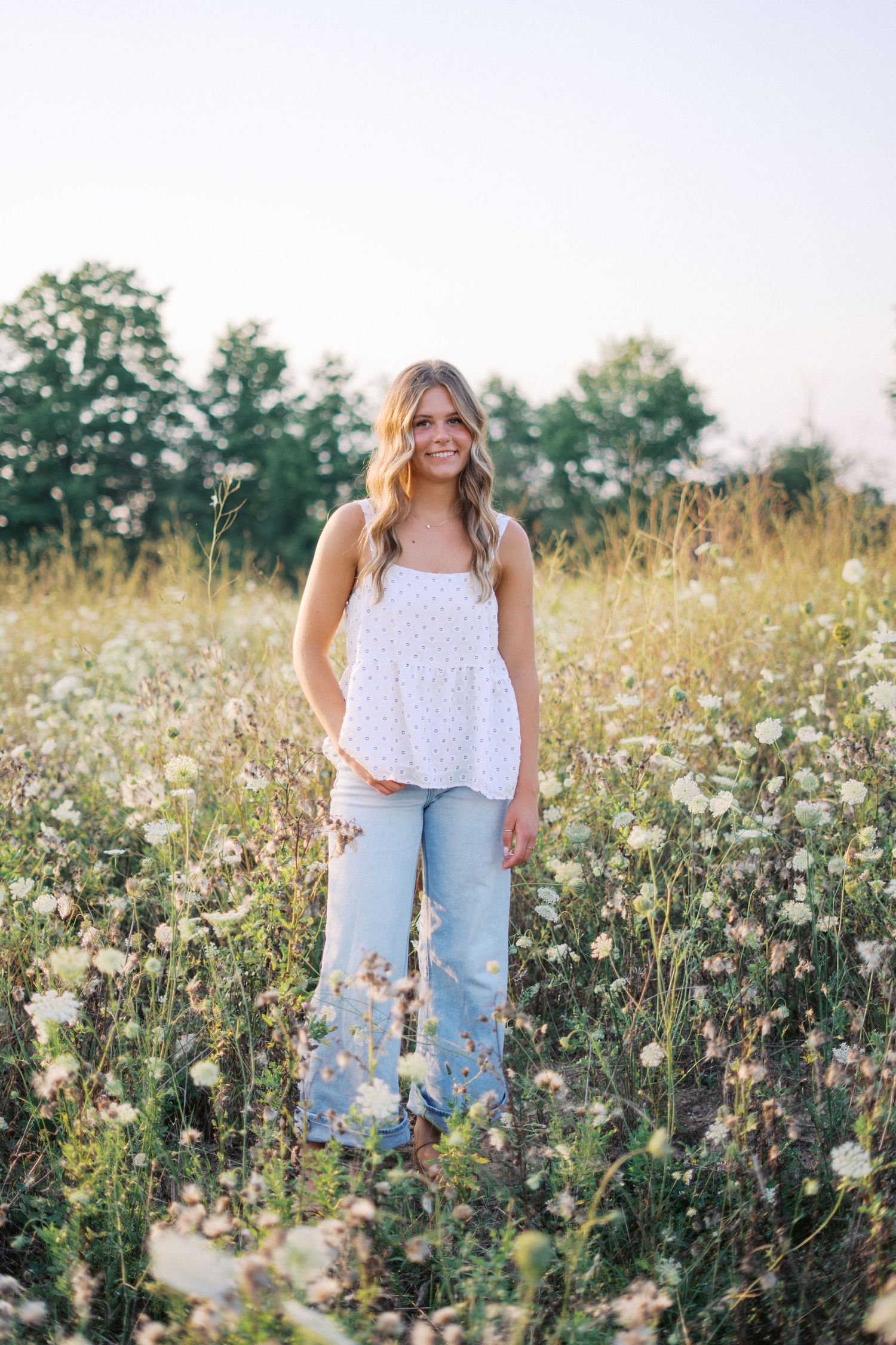Summer fashion photography in a wildflower field featuring light denim and a white top.