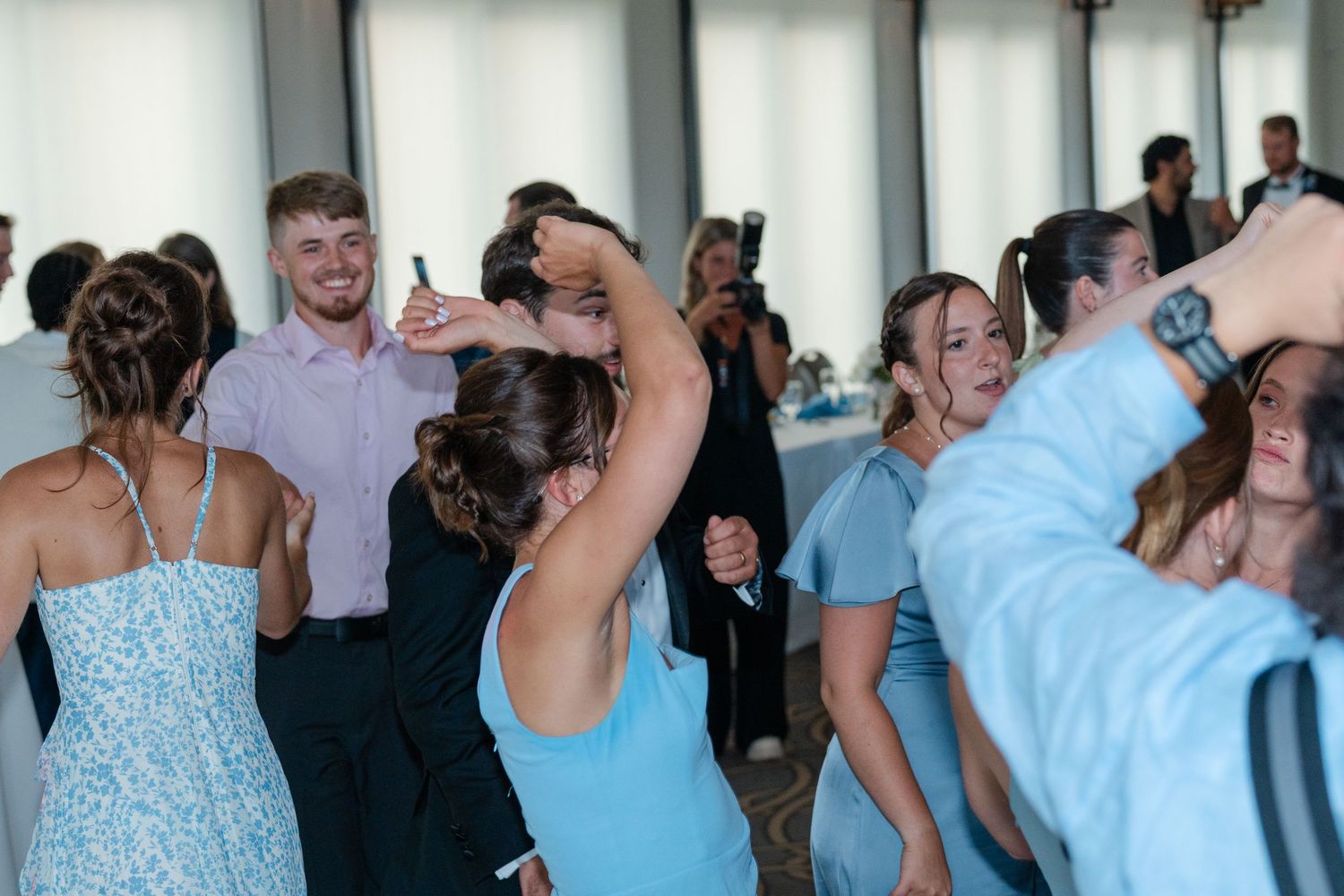 Wedding guests dancing and celebrating on the dance floor in pastel attire.
