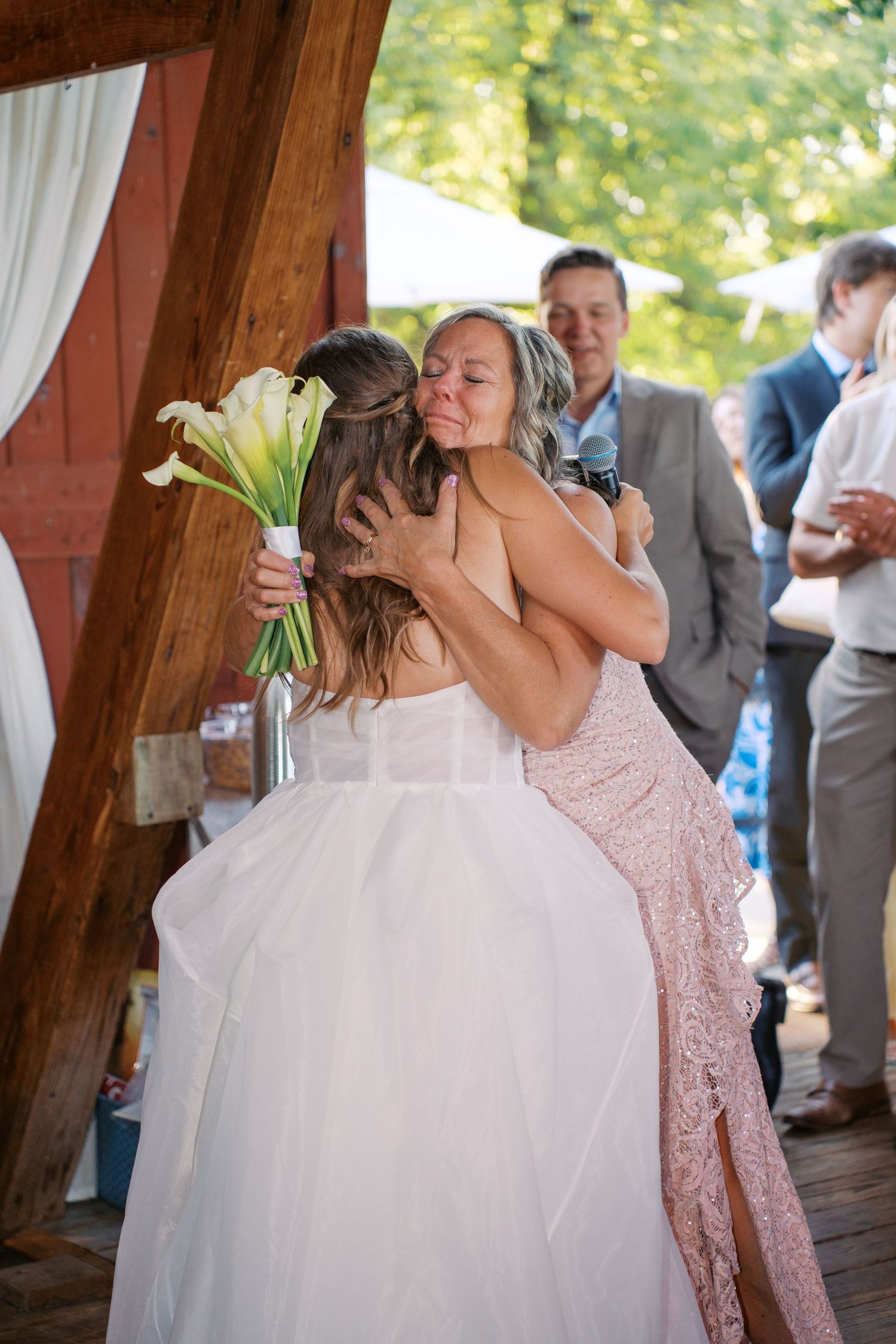 Emotional moment shared during wedding reception in rustic barn setting.