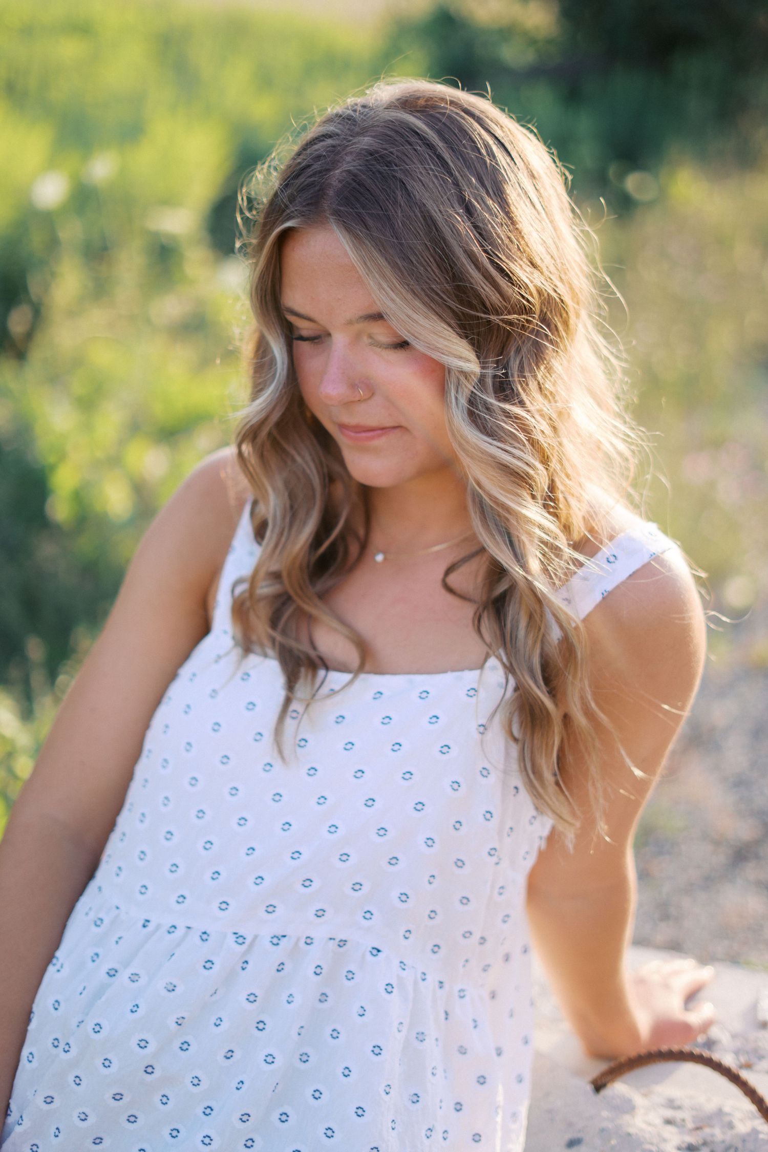 Close-up portrait featuring a white polka dot tank top against a sunlit natural background.
