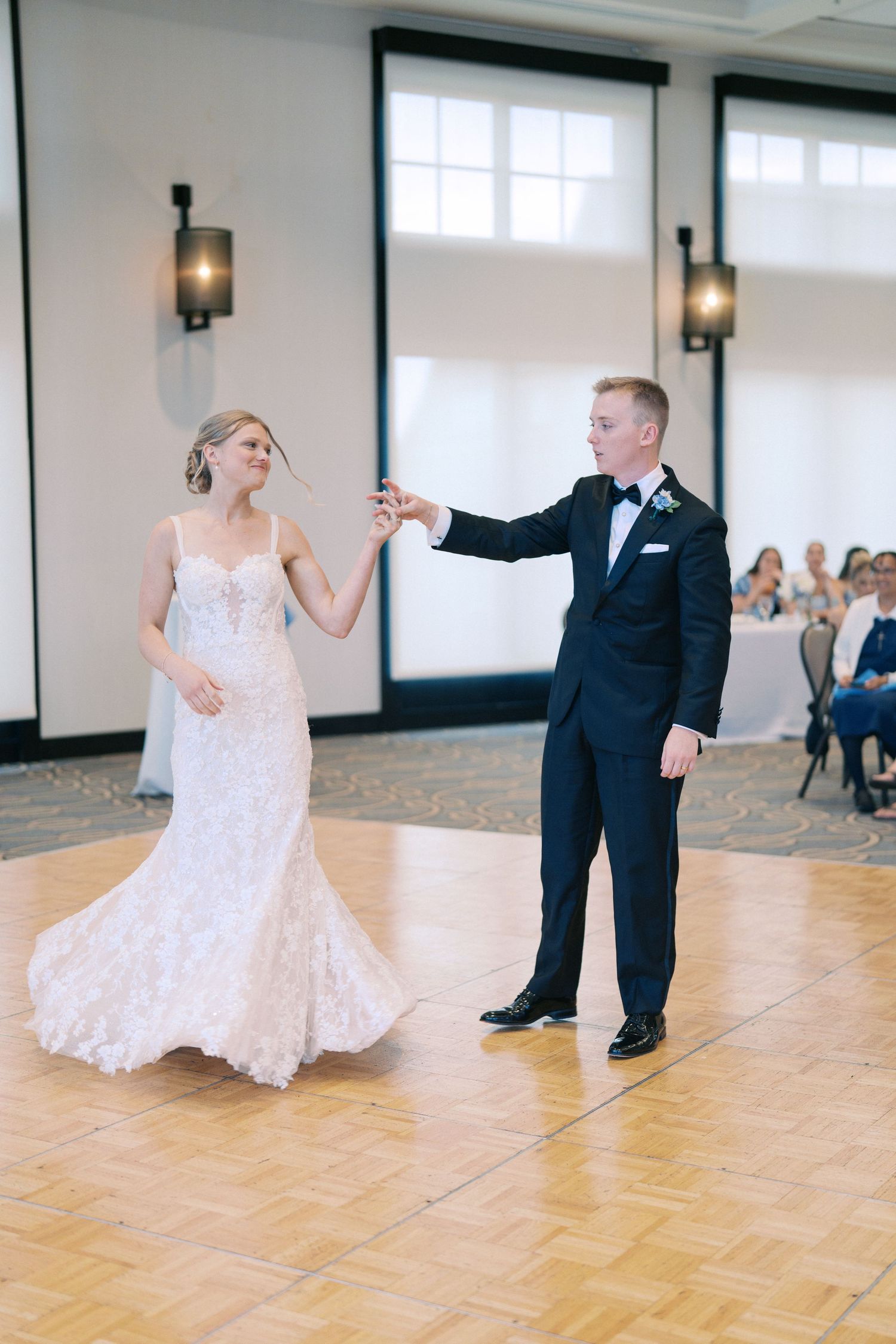 Wedding couple dancing and twirling on a parquet floor in an elegant reception venue.