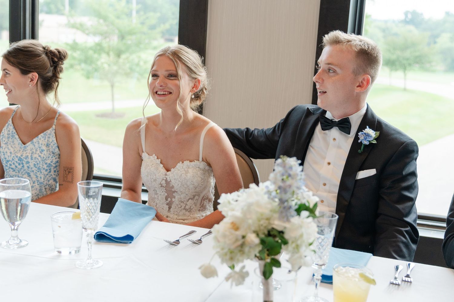 Wedding party seated at head table during reception with blue and white decor.