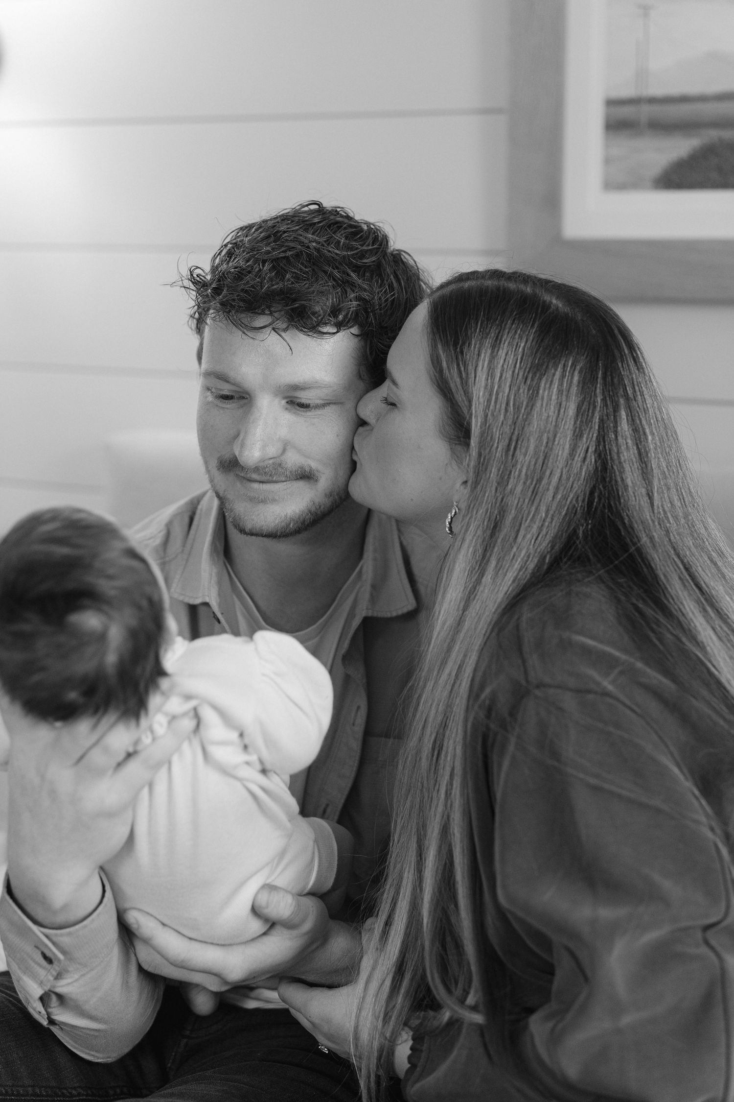 Intimate family moment with newborn baby in white clothing.