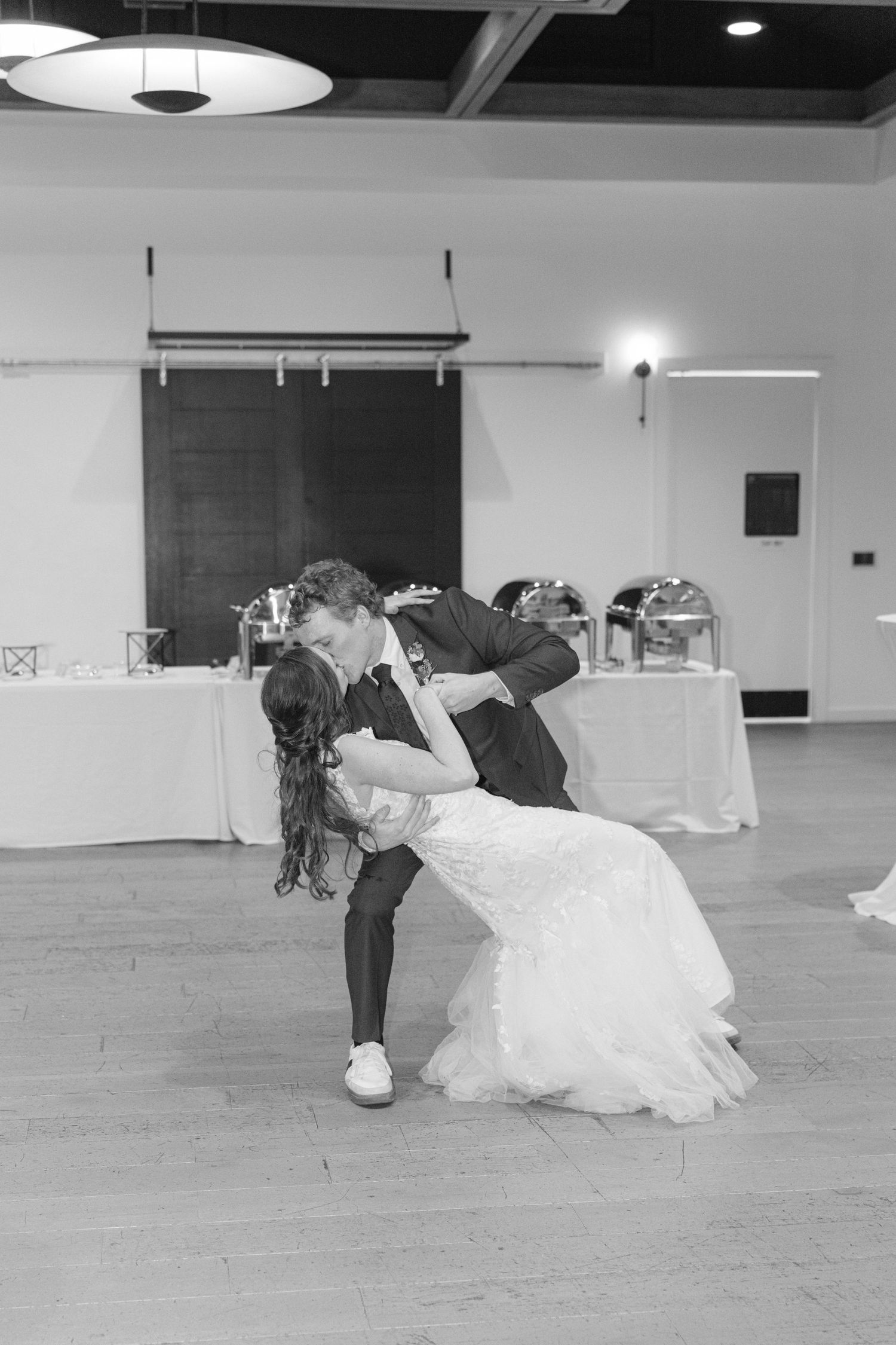 A dramatic dance dip captured during a wedding reception on a hardwood floor.