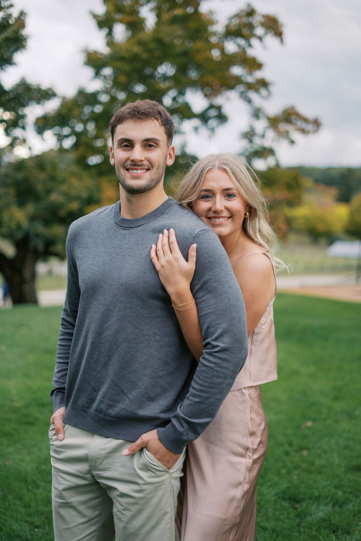 A couple in coordinated casual outfits posing together on a grassy lawn.