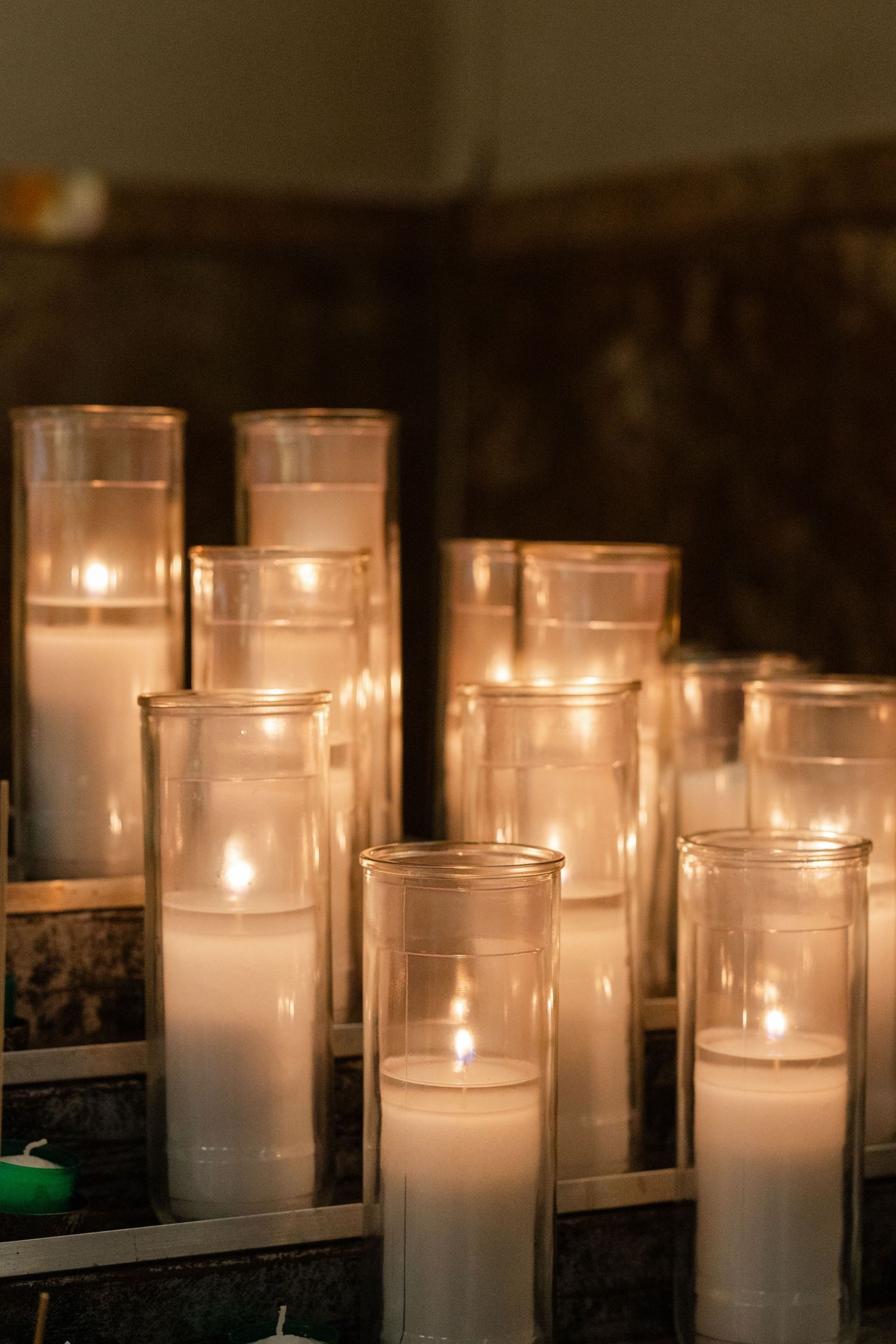 Row of glowing white votive candles creates romantic ambiance in dark setting.