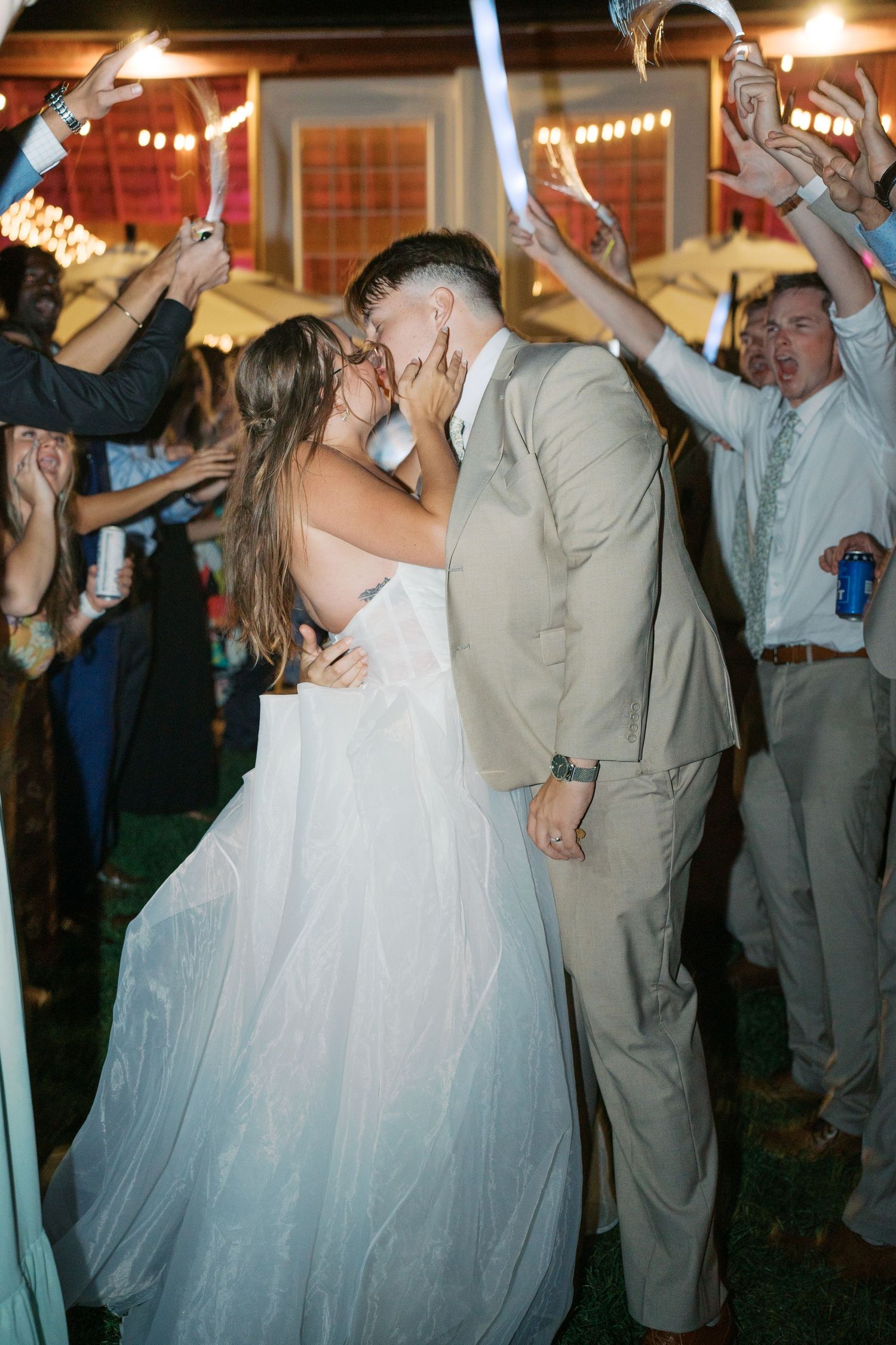 Wedding party dancing and celebrating with raised arms at an indoor reception venue.