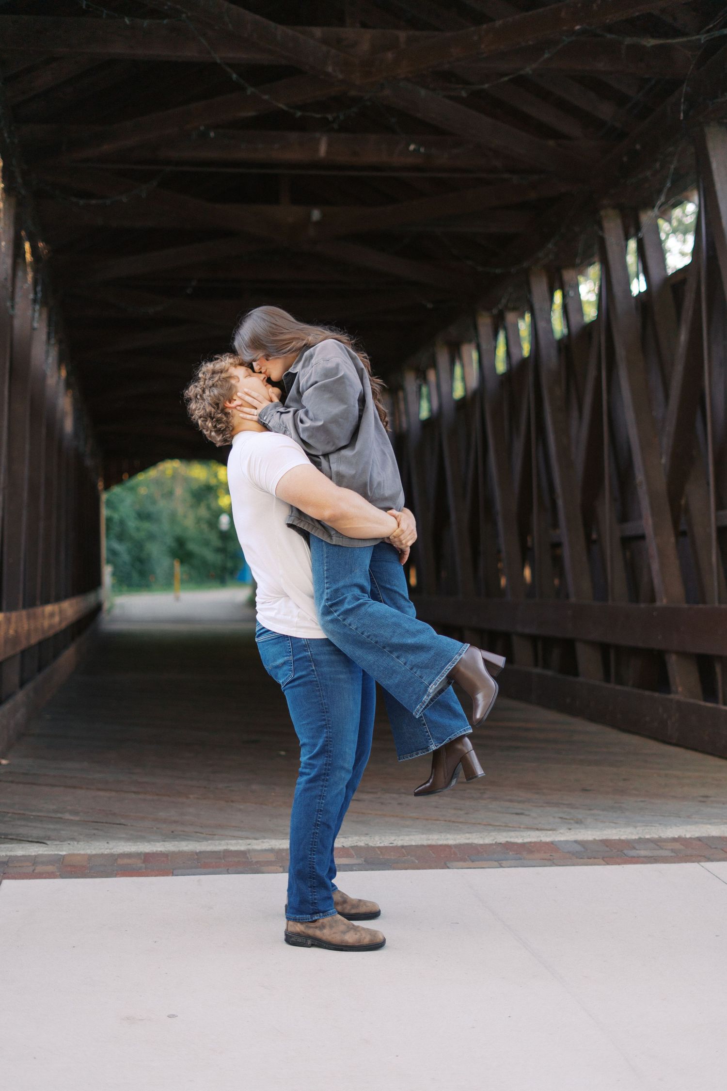 Romantic couple embracing inside a rustic covered bridge.