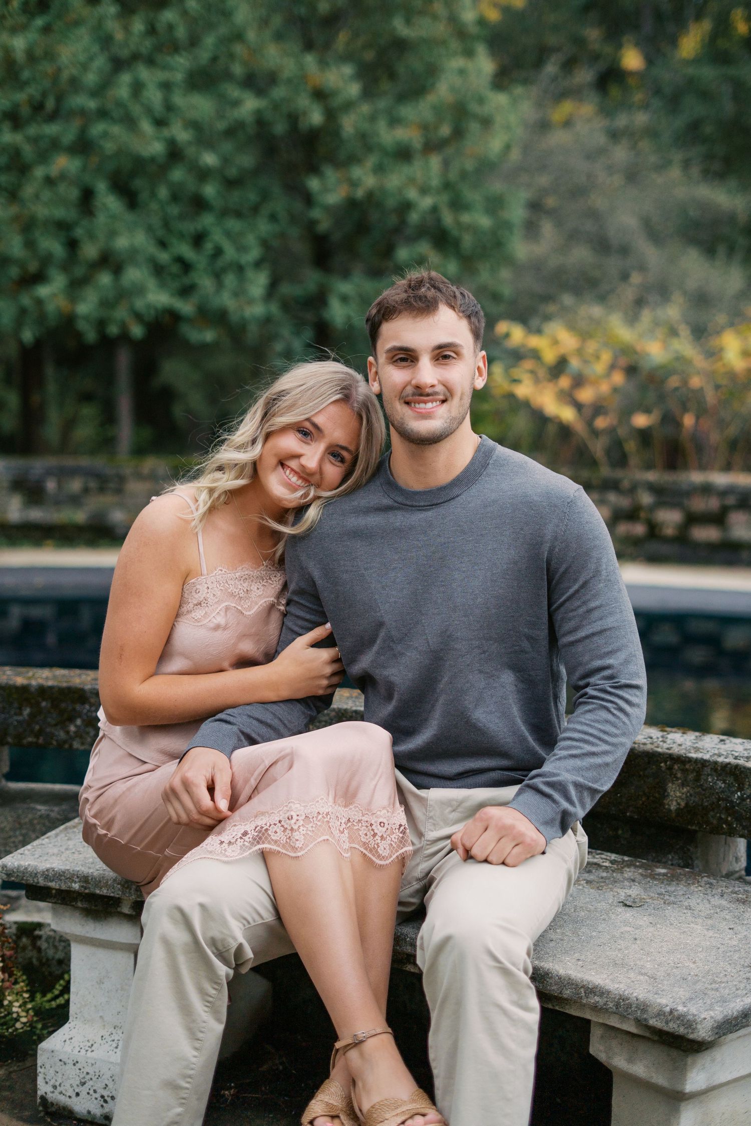 A romantic couple sitting together on stone steps in an outdoor garden setting.