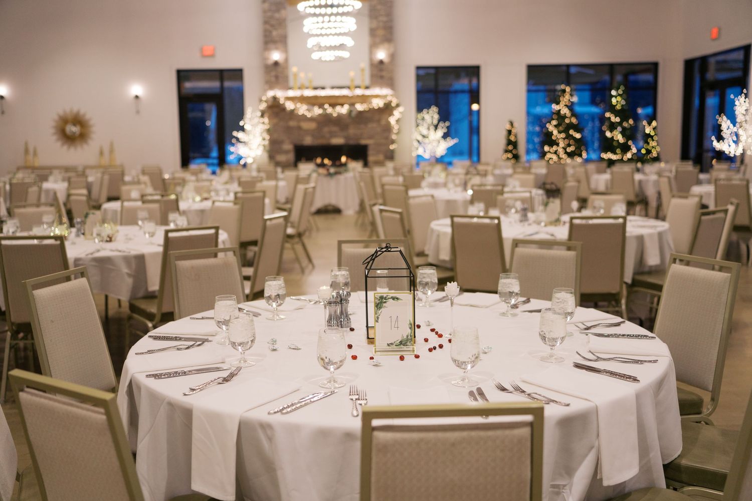 Wedding reception tables arranged with white linens under crystal chandeliers in an elegant ballroom.