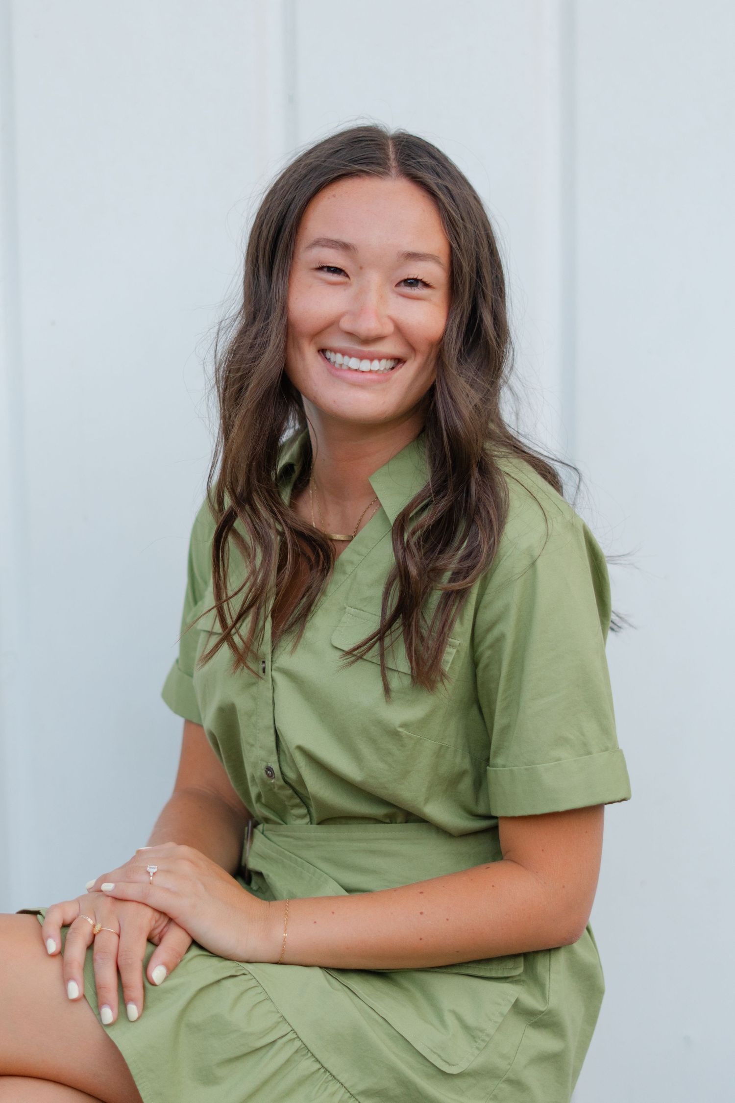 Portrait series showing joyful expressions while wearing a sage green dress against a white background.