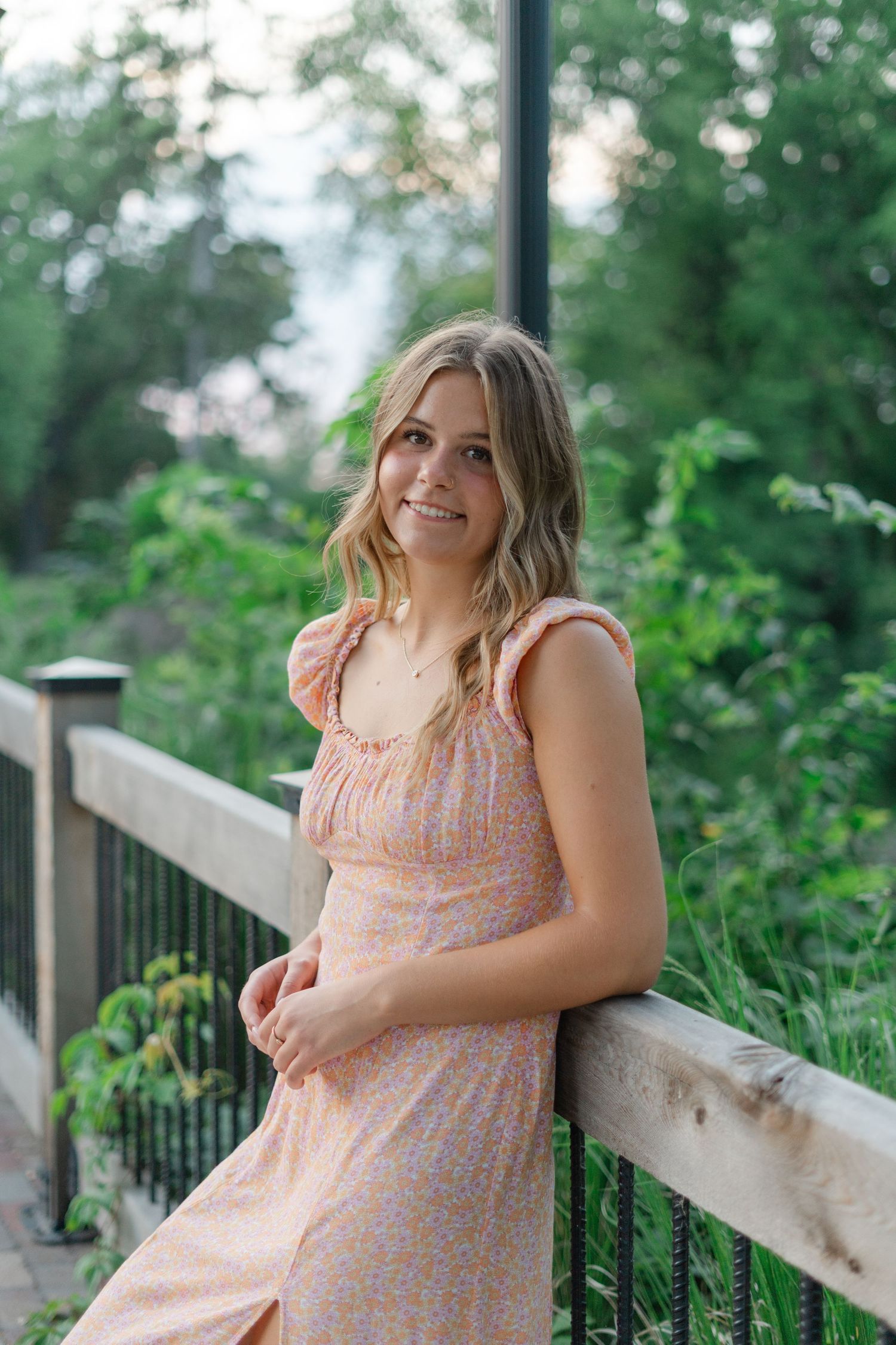 Summer portrait on a wooden deck surrounded by lush greenery.