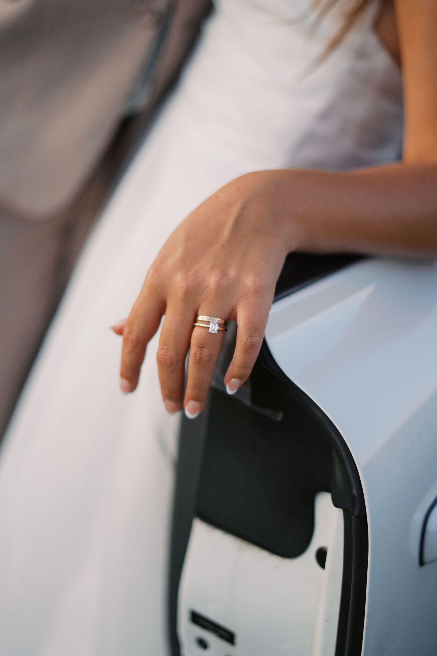 Close-up shot of hands resting on a white car door handle.