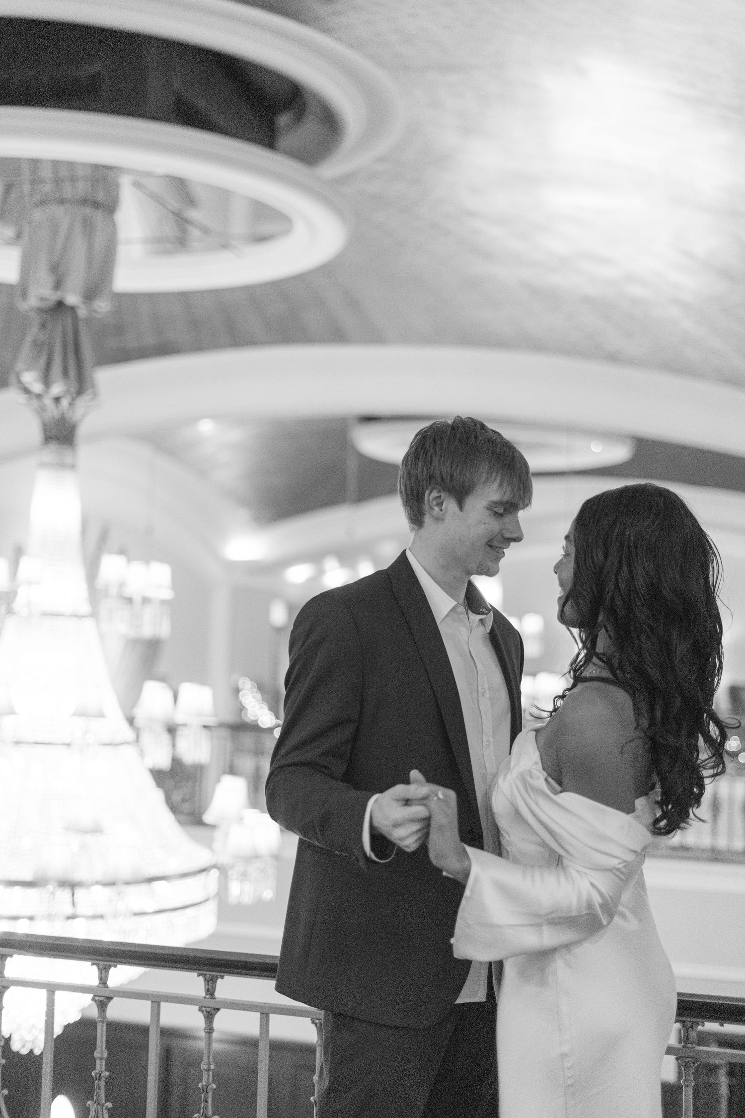 A couple shares a romantic dance in an elegant black and white ballroom setting.