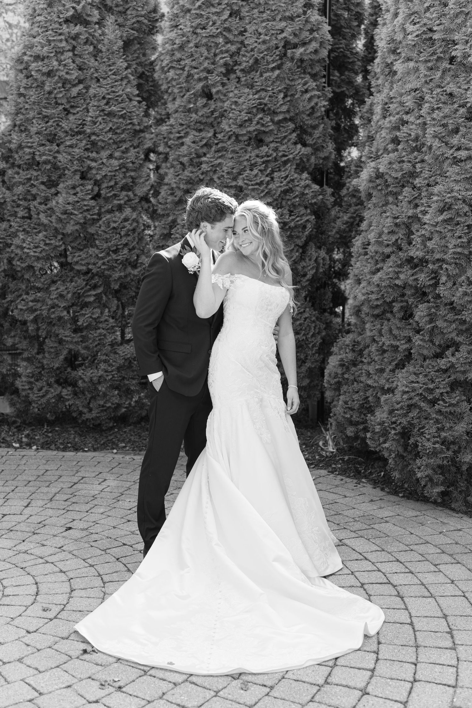 A black and white photo of a couple dancing on a brick patio during their wedding.