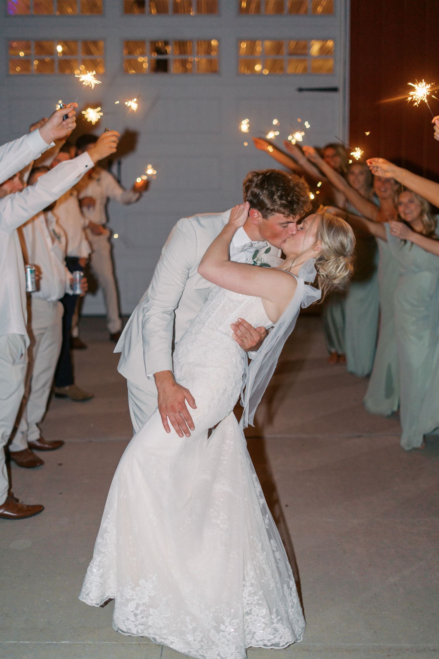 Wedding couple and guests dancing with sparklers during an evening reception celebration.