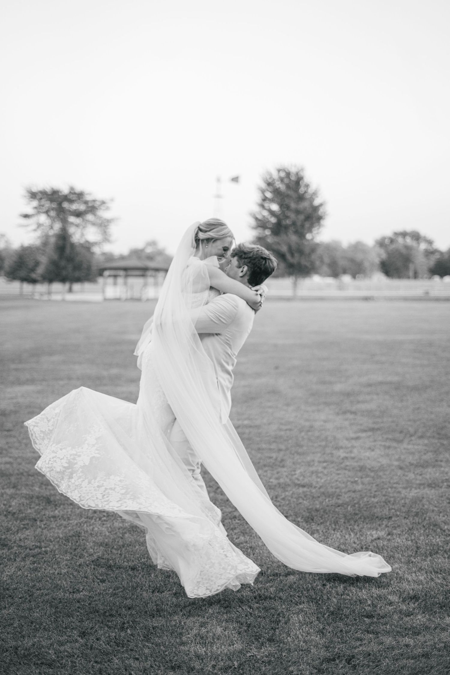 Flowing white wedding dress billows dramatically in black and white photography.