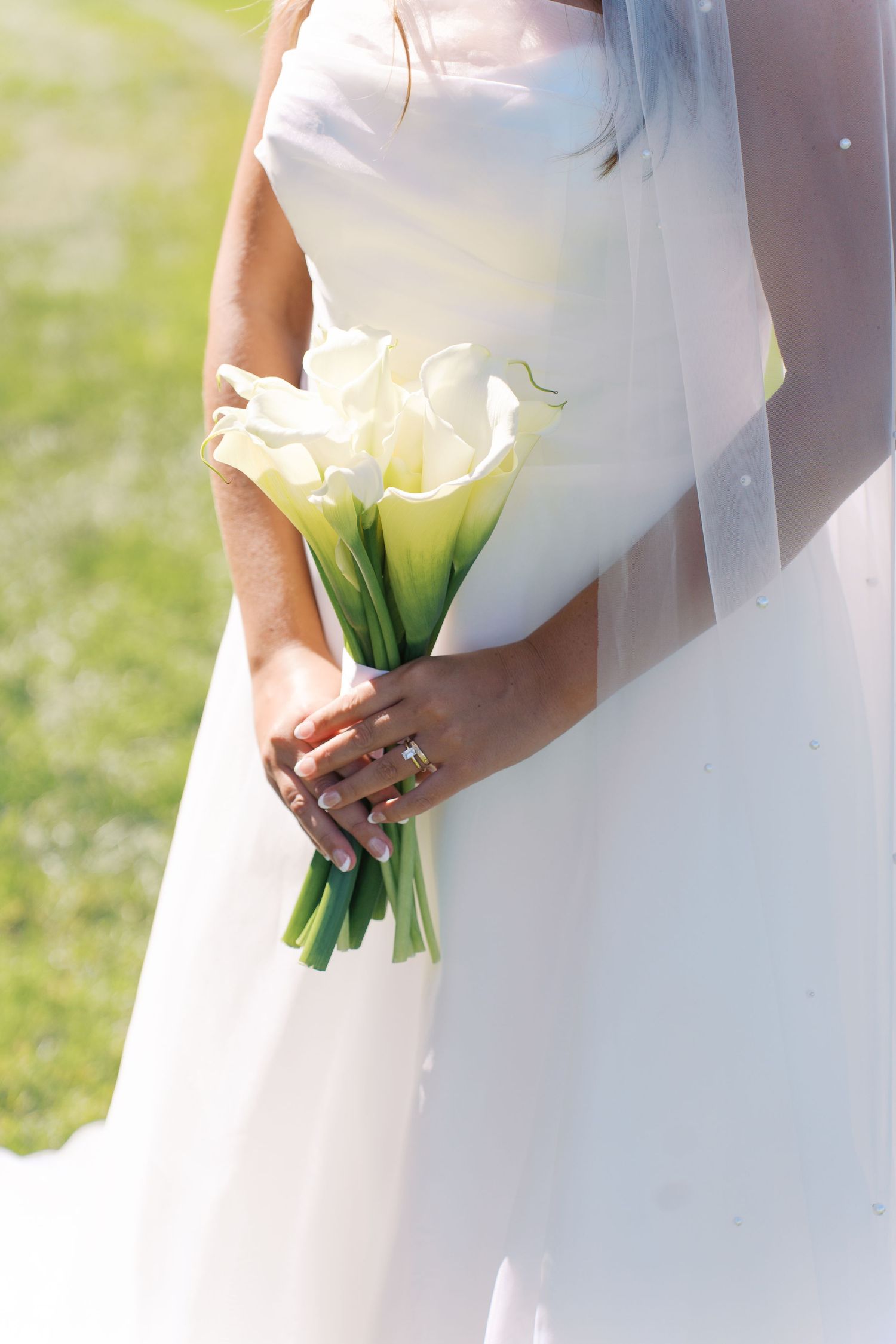 Close-up shots of a bride holding an elegant white calla lily bouquet.