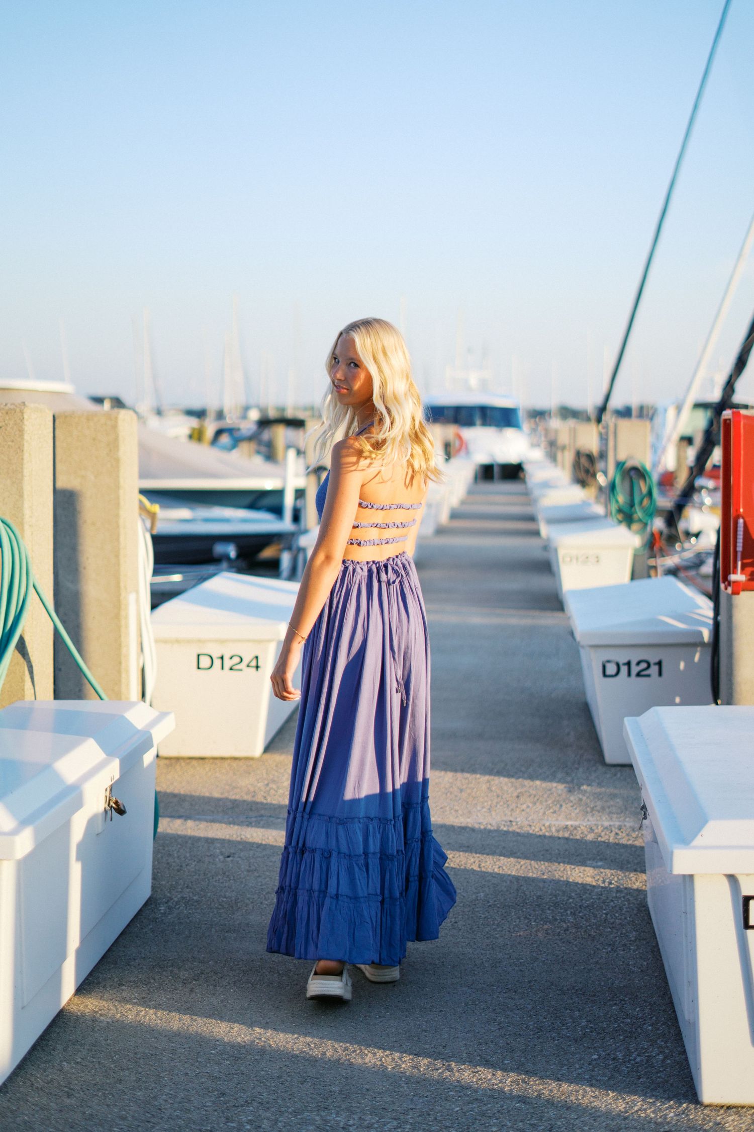 Blue dress photoshoot along marina dock with numbered storage units.