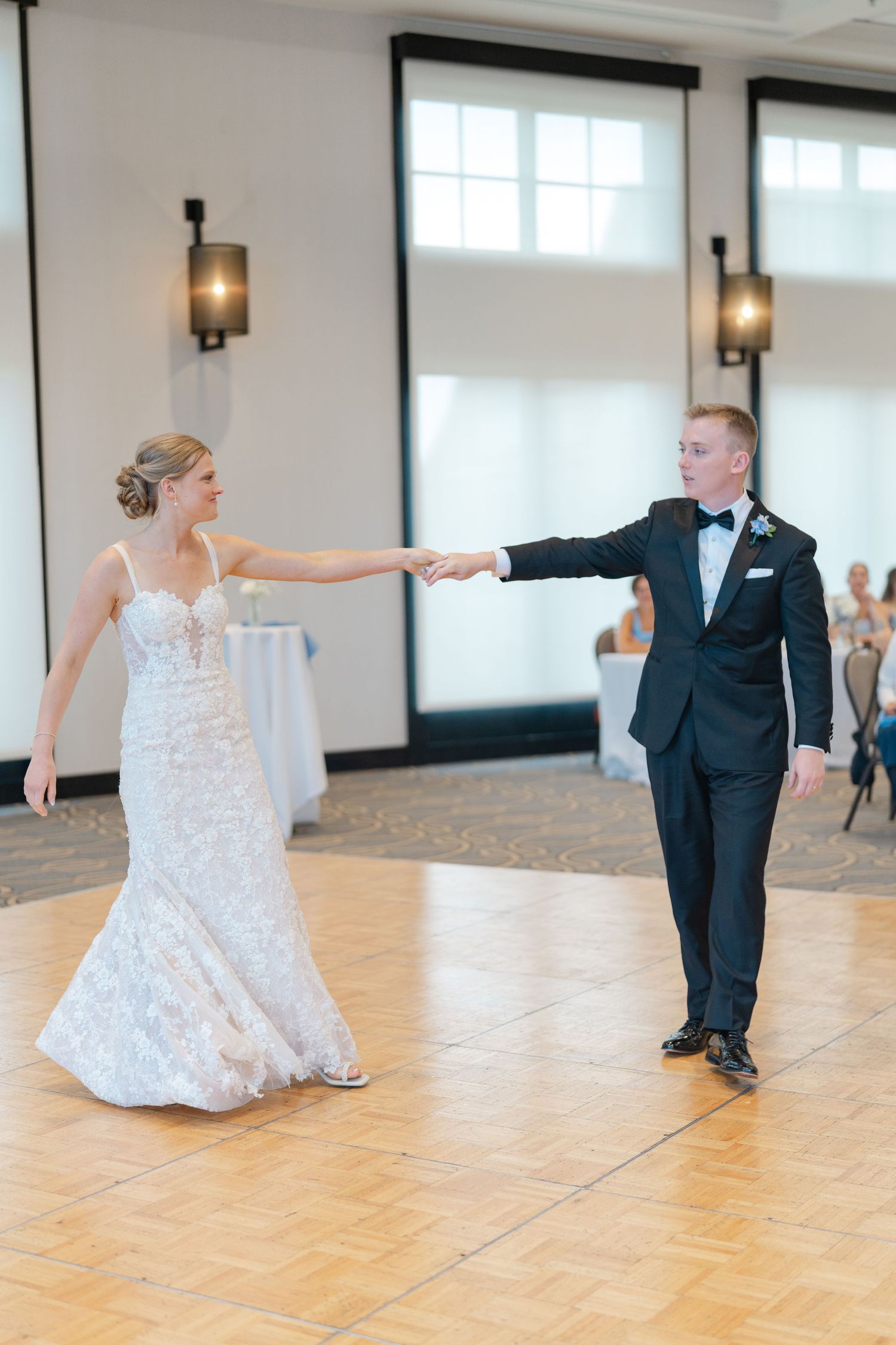 Elegant first dance moment on wooden dance floor at wedding reception.