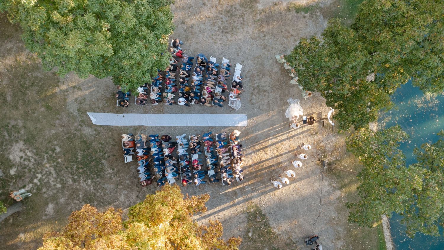 Aerial view of a parking lot with cars near trees and a lake.