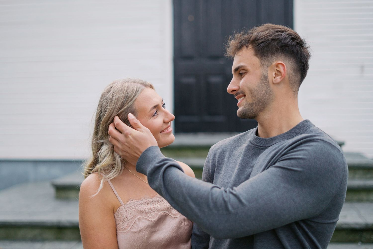 Intimate moment captured between a couple outside a white church building.