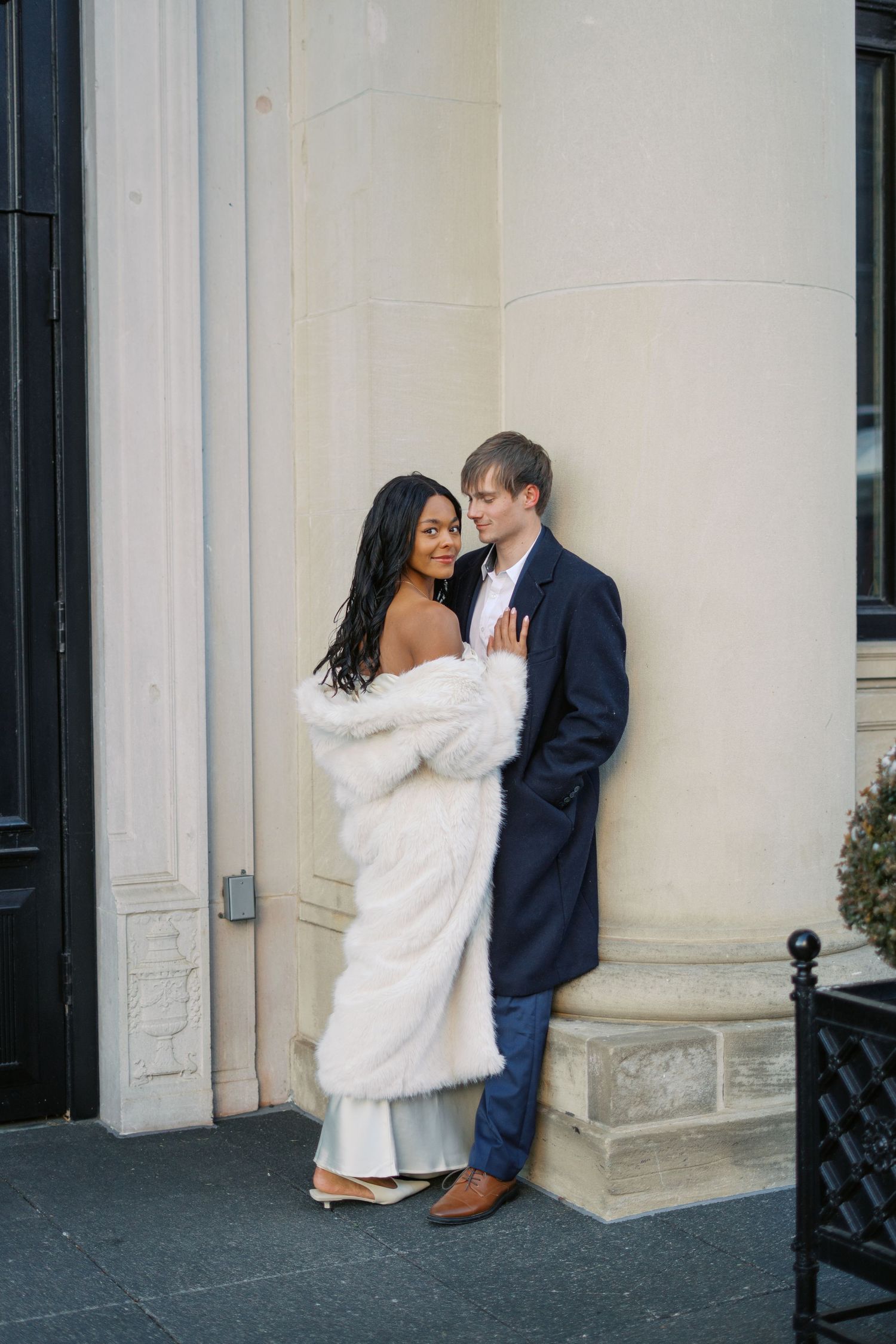 Intimate wedding portraits against a classic white building with black doors.