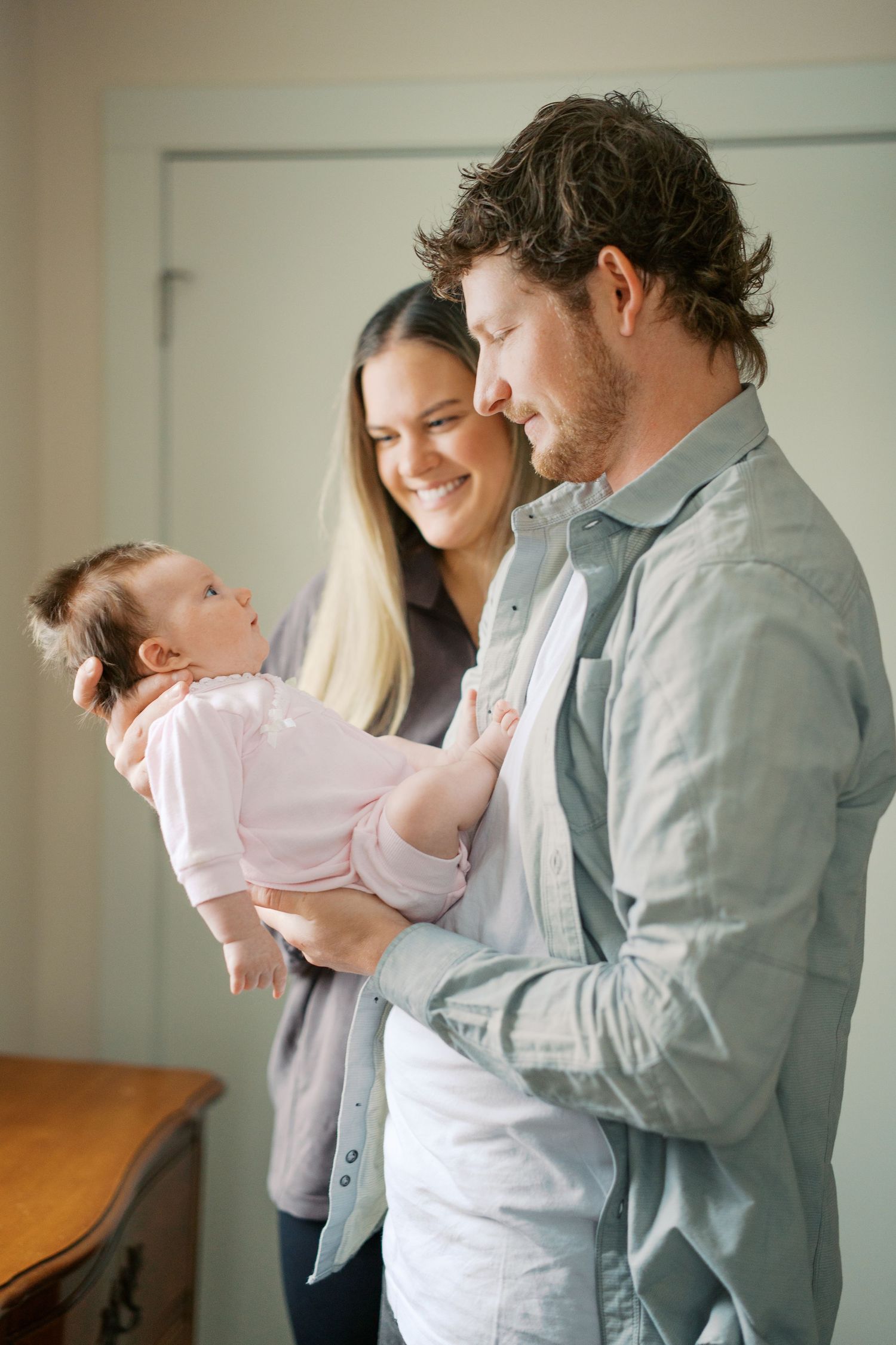 Parents sharing tender moment with baby in bright indoor setting.
